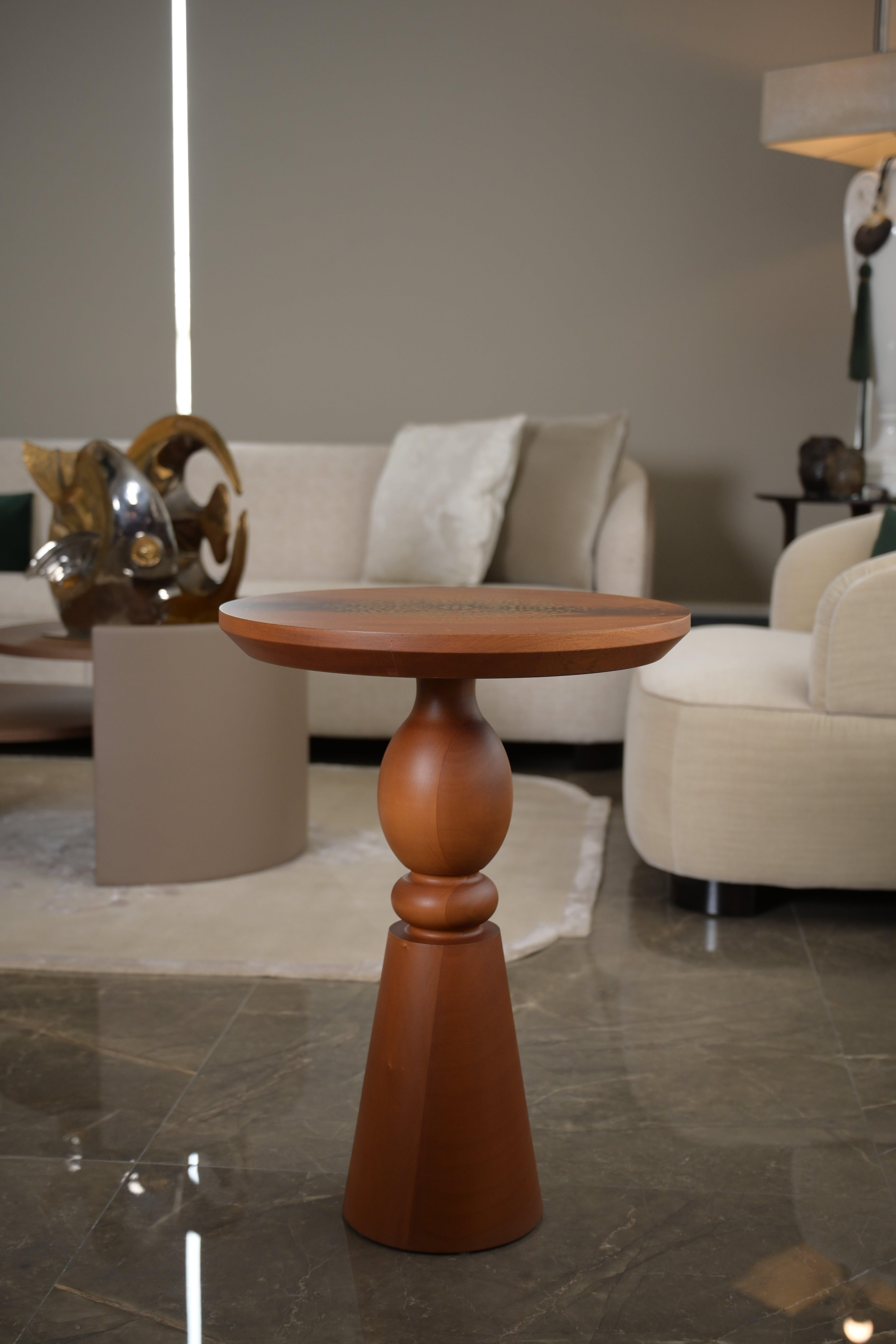 This lamp table is crafted from solid mahogany wood, showcasing a rich, matte finish that highlights the natural beauty of the grain. The table features a turned base, adding a touch of classical charm to its design. The round top is a standout,