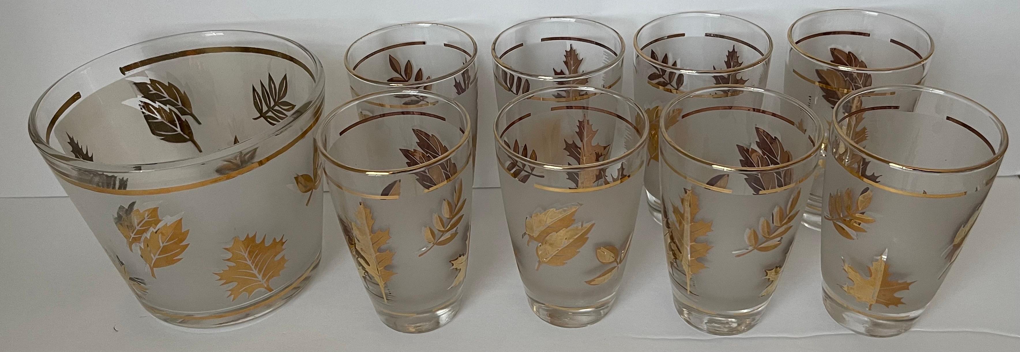 Set of 8 Libby Golden Foliage leaf glasses and ice bucket. Frosted and clear glass with gold overall leaf motif and gold banding. 
Each glass measures: 5” tall x 3”’wide and Ice bucket measures: 6” wide x 5” tall.