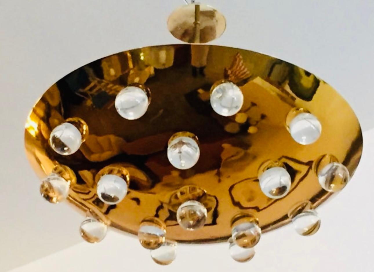 A stunning 1960s French polished solid brass round disc fixture with 16 solid glass orbs. Five-light sources which emit light downward through the glass as well as up toward the ceiling. The ceiling pole can be lengthened or shortened. Rewired and