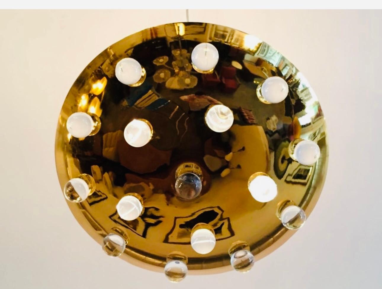 Un superbe luminaire à disque rond en laiton massif poli des années 1960, avec 16 orbes en verre massif. Sources de cinq lumières qui émettent de la lumière vers le bas à travers le verre ainsi que vers le haut en direction du plafond. Le poteau de