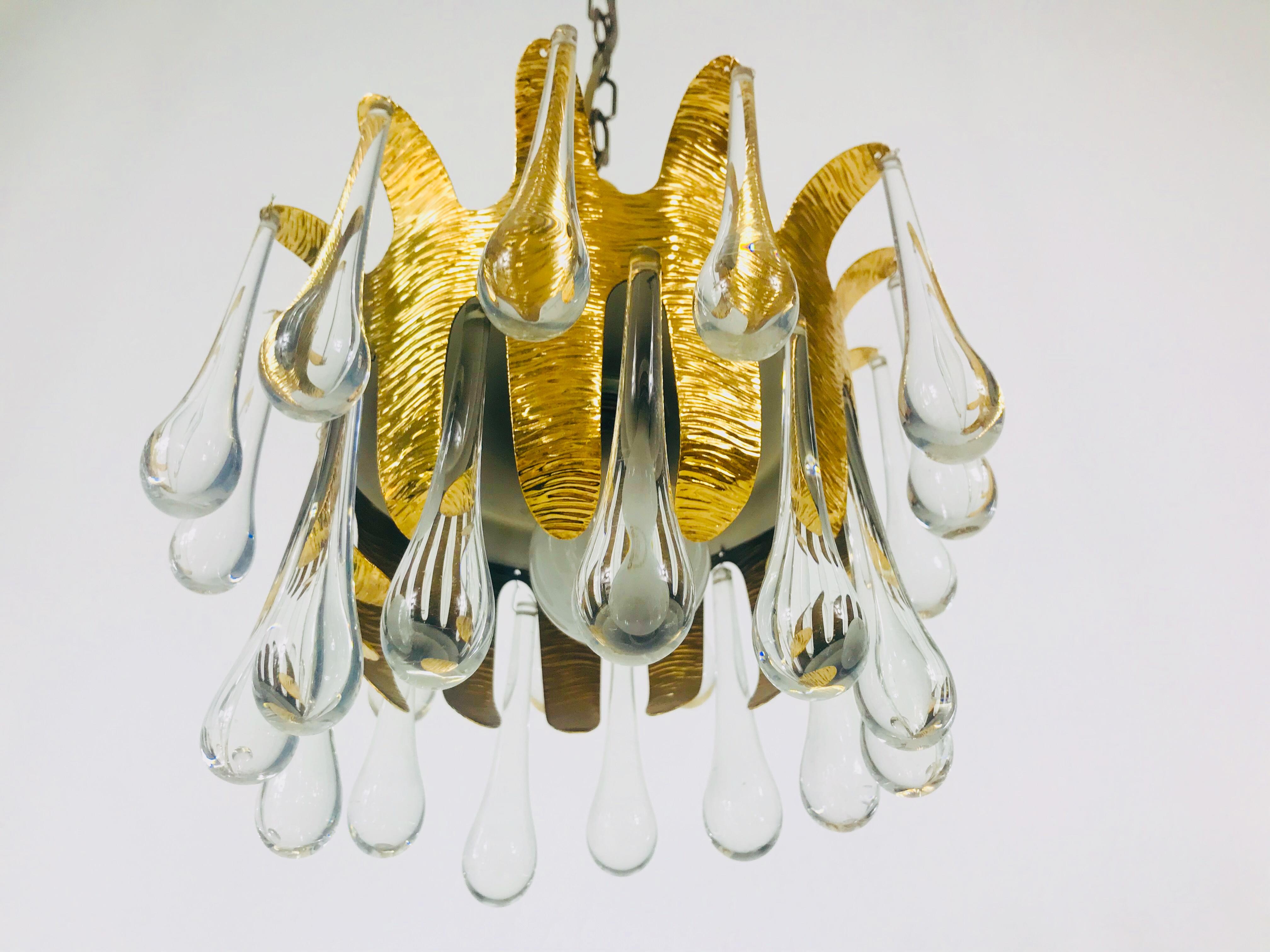 An extraordinary chandelier by Palwa made in Germany in the 1960s. The lamp has a very elegant design. It is made in the period of Hollywood Regency. Round golden gilded brass body with one E27 socket. The body is surrounded with very elegant