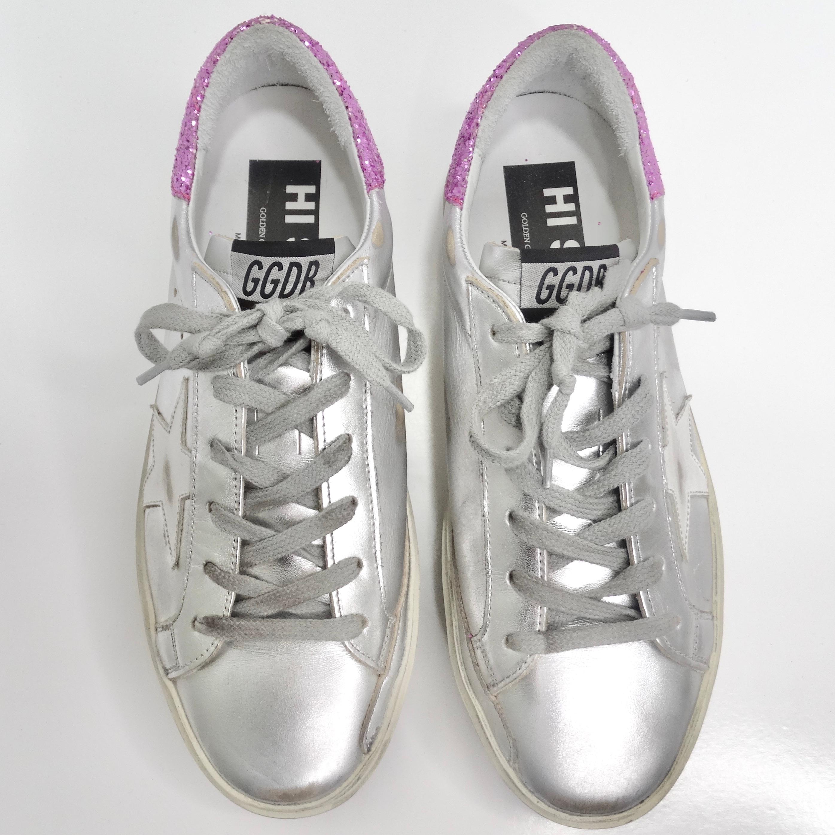 Introducing the epitome of urban glamour, the Golden Goose Silver/Pink Leather And Glitter Superstar Low Top Sneakers. Elevate your style with these metallic silver low top sneakers that effortlessly embody the signature Golden Goose distressed
