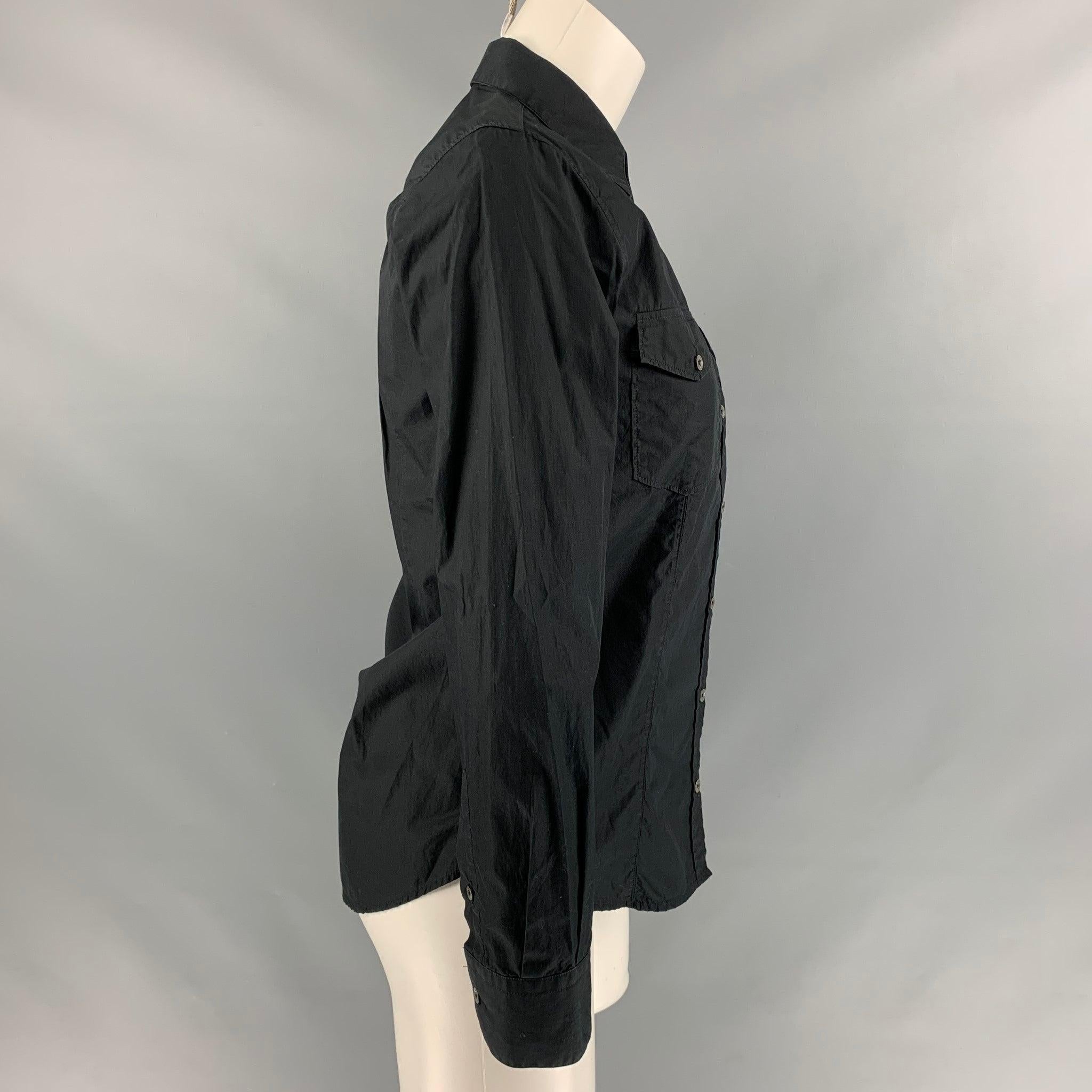 GOLDEN GOOSE long sleeve blouse comes in black cotton fabric featuring a straight collar, two patch pockets with flap at front, two gold stripe at side seam and a button up closure. Made in Italy.Excellent Pre-Owned Condition. 

Marked:   S