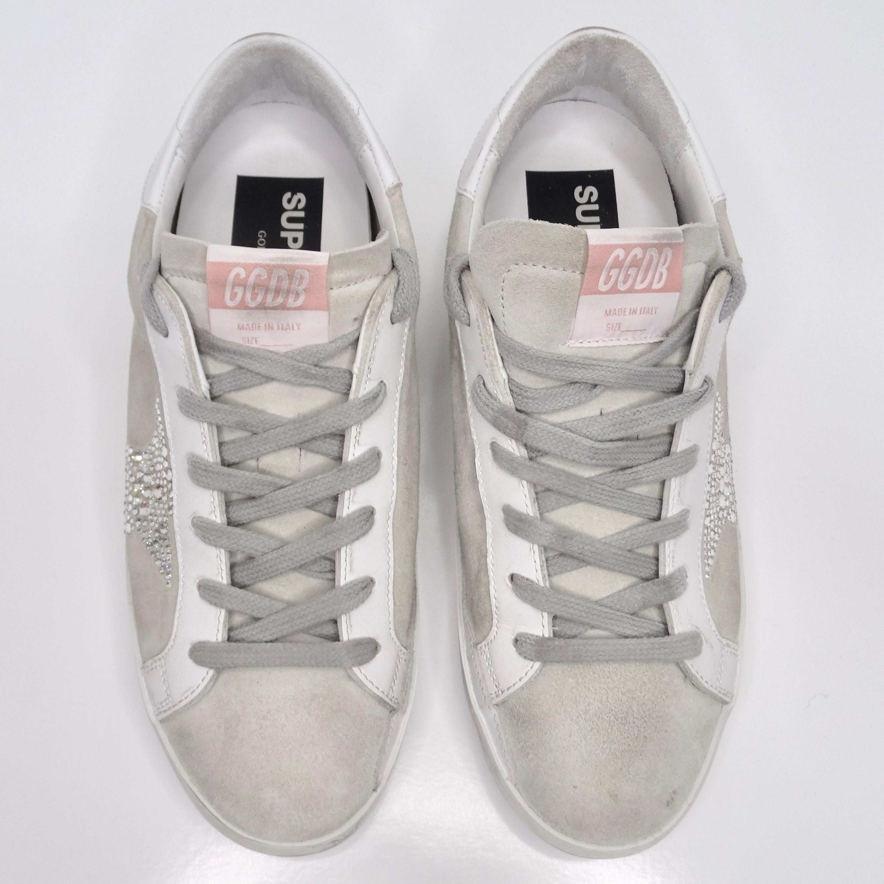 Elevate your footwear collection with the opulent charm of Golden Goose Superstar Swarovski Crystal Suede Sneakers. Crafted in an exquisite shade of grey suede, these low top sneakers boast an unmistakable Golden Goose distressed motif that exudes