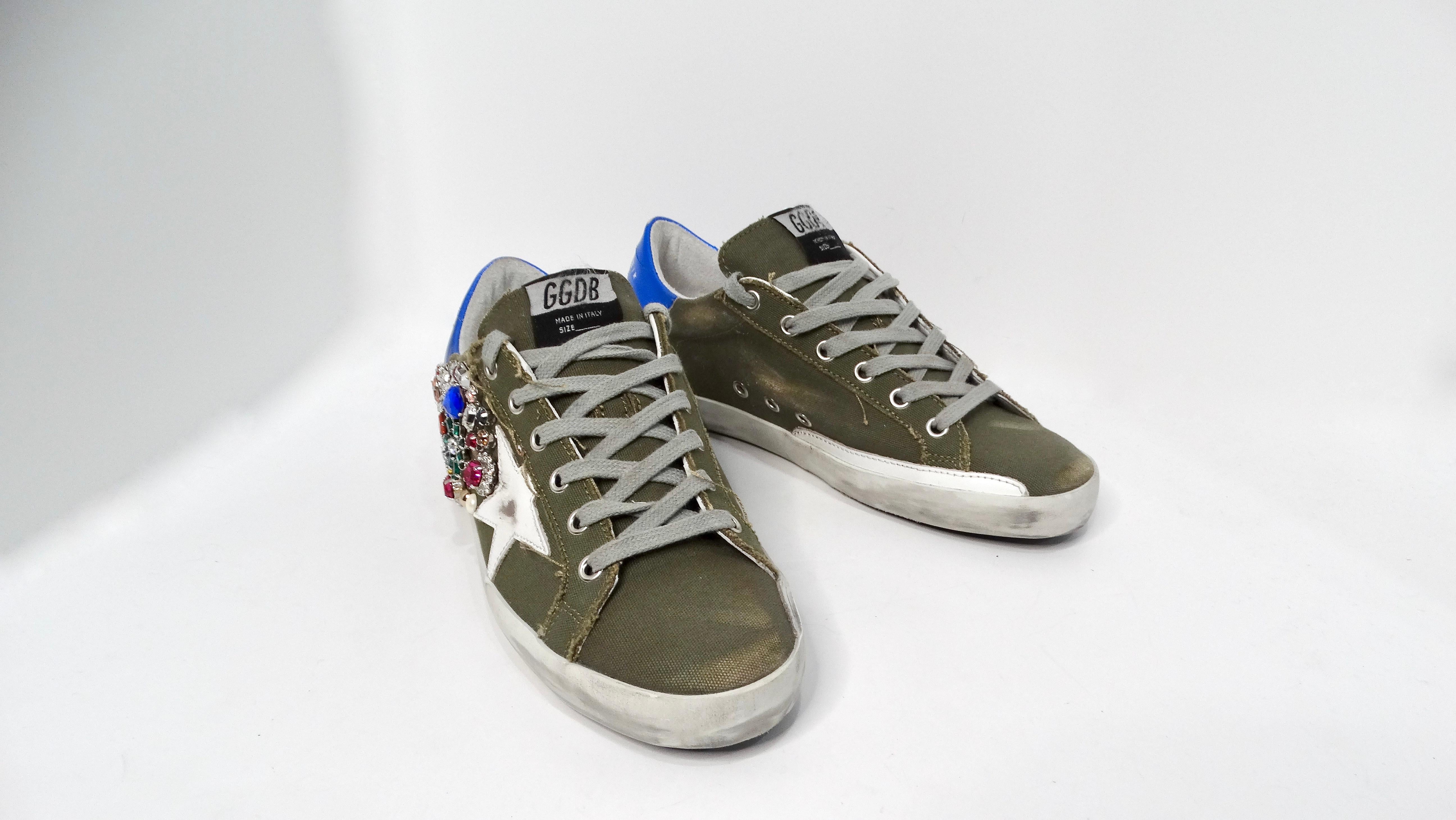 Le sneakers Superstar di Golden Goose impreziosite da cristalli Swarovski sono una straordinaria fusione di street style e lusso. Fabrice in un esclusivo tessuto grigio-verde, queste sneakers presentano cristalli Swarovski multicolore che adornano