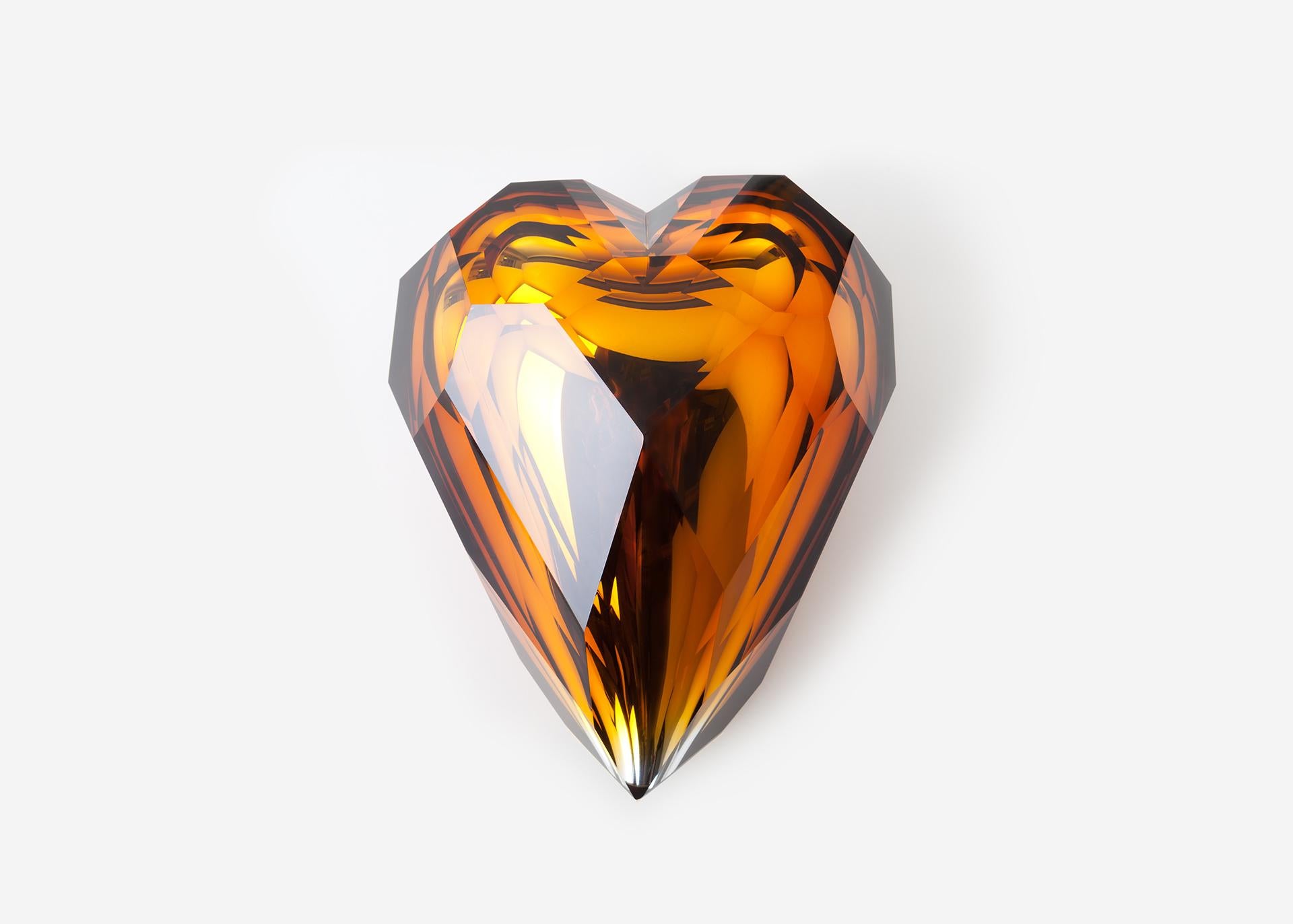 Golden heart by Dechem Studio.
Dimensions: H 29 cm.
Materials: glass, brass.

This glass piece combines the soft shape of a coloured hand blown heart with an angular hand-faceted finishing. These contrasting features give it a multilayered