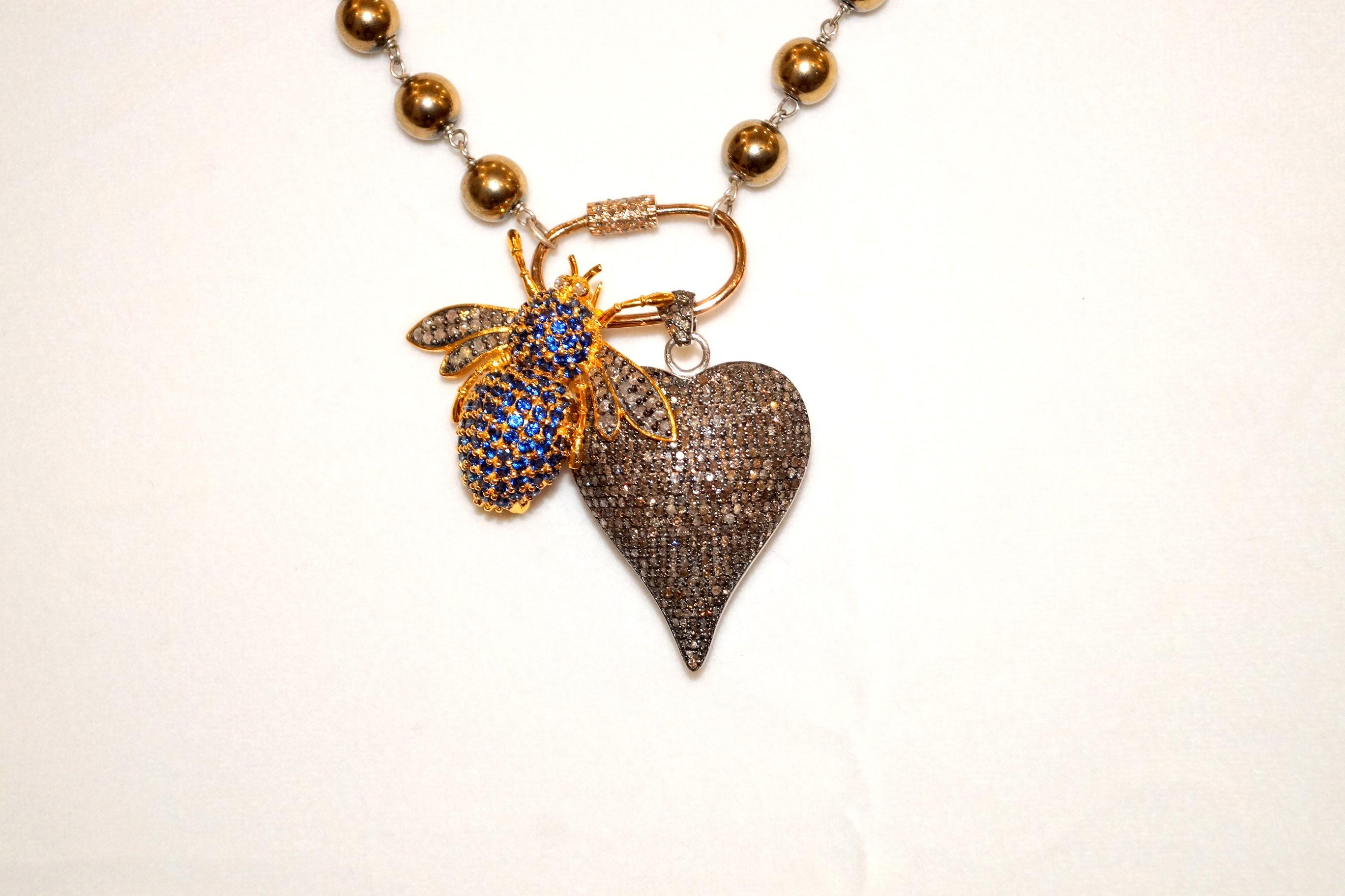 Elevate your jewelry collection with this luxurious designer necklace, featuring golden hematite beads strung together with sterling silver links. The necklace is adorned with an exquisite sterling silver carabiner lock, embellished with pave