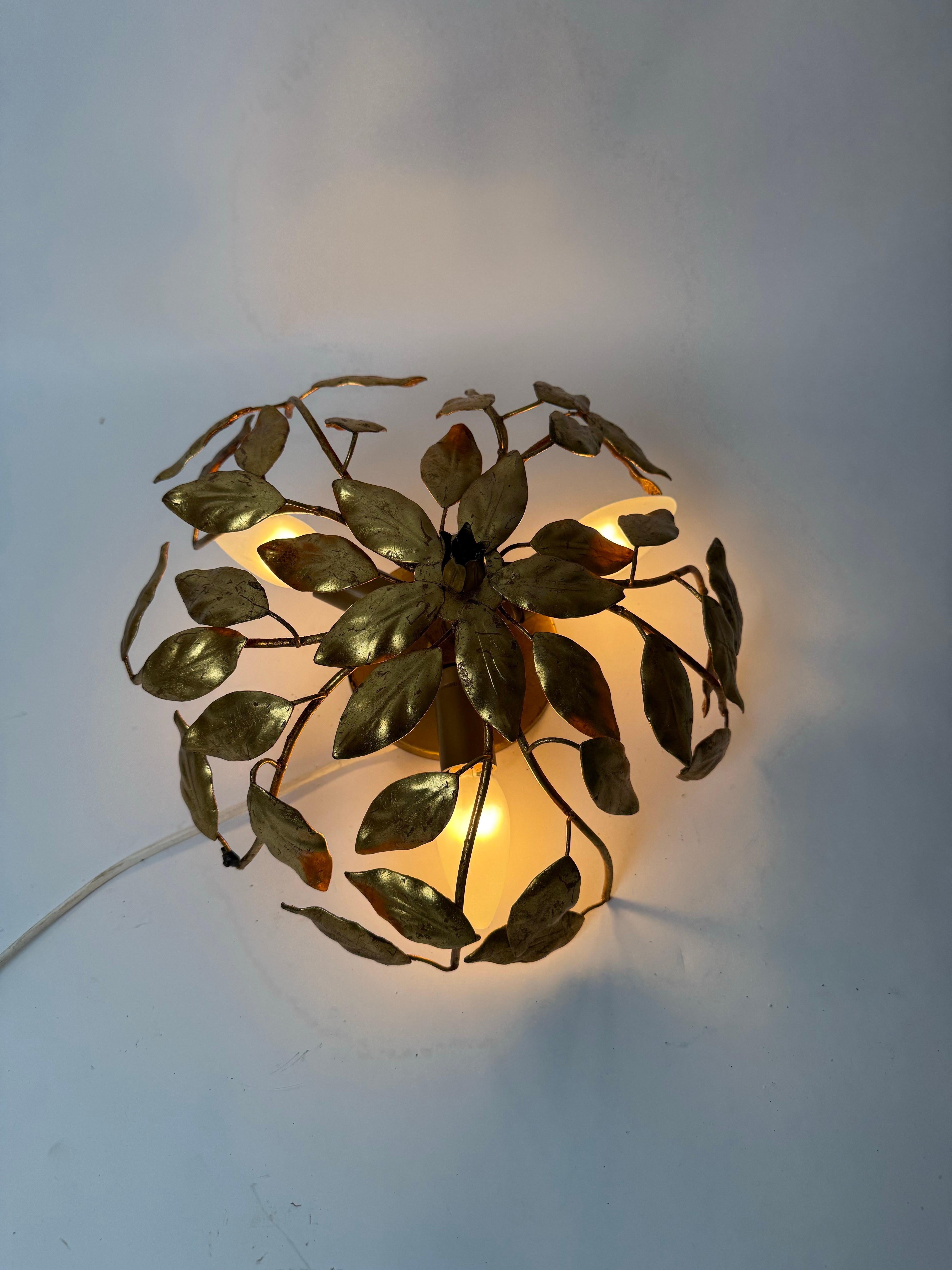 This beautiful ceiling lamp from Italy is truly one-of-a-kind. It's from the 1960s or 1970s, and it's in pristine condition. The craftsmanship is truly remarkable. The hand-gold-covered details are stunning, and the delicate leaves feel like they're