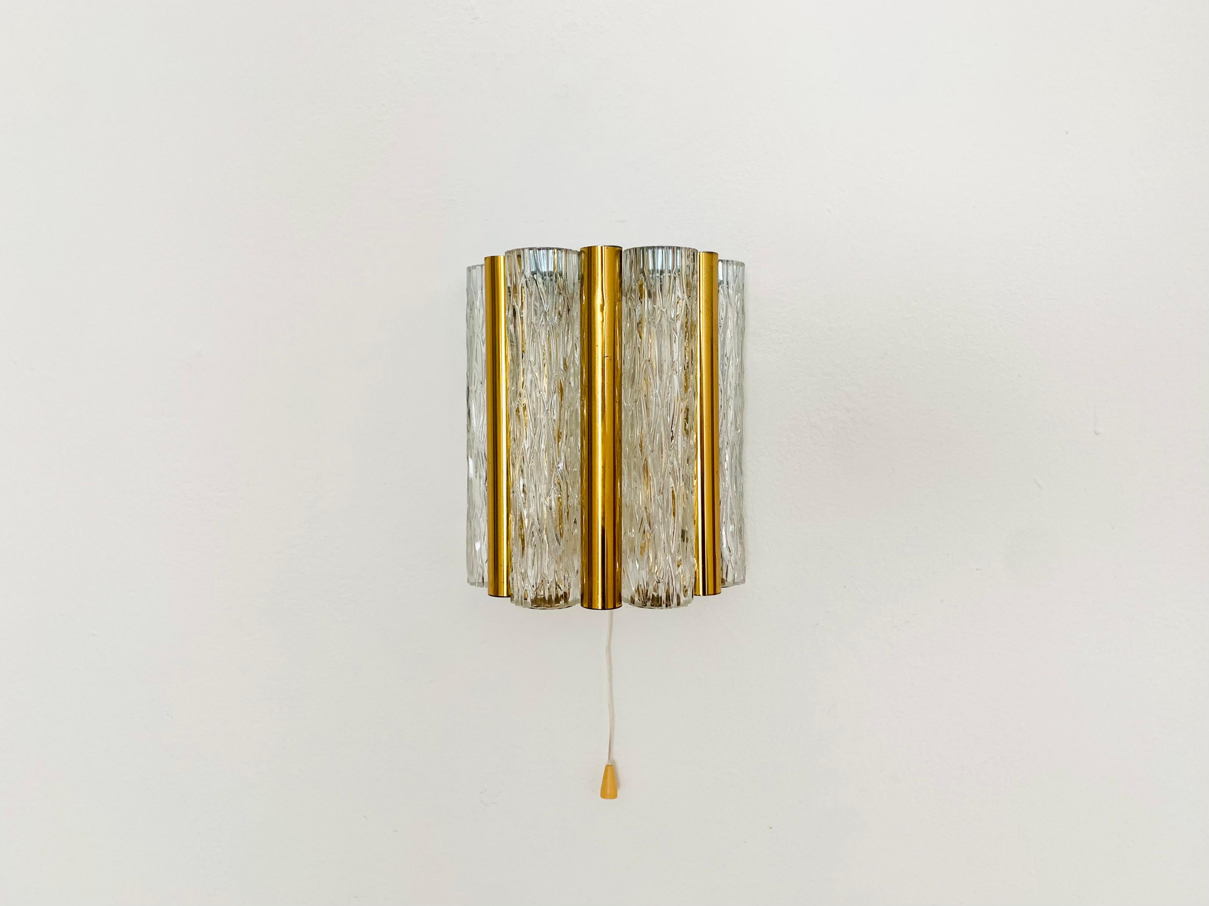 Very beautiful and elegant ice glass wall lamp from the 1960s.
The lamp is of high quality.
The structured glass creates a wonderful sparkling and noble light.

Manufacturer: Kaiser Lights/ Kaiser Idell

The lamp has an integrated switch but can