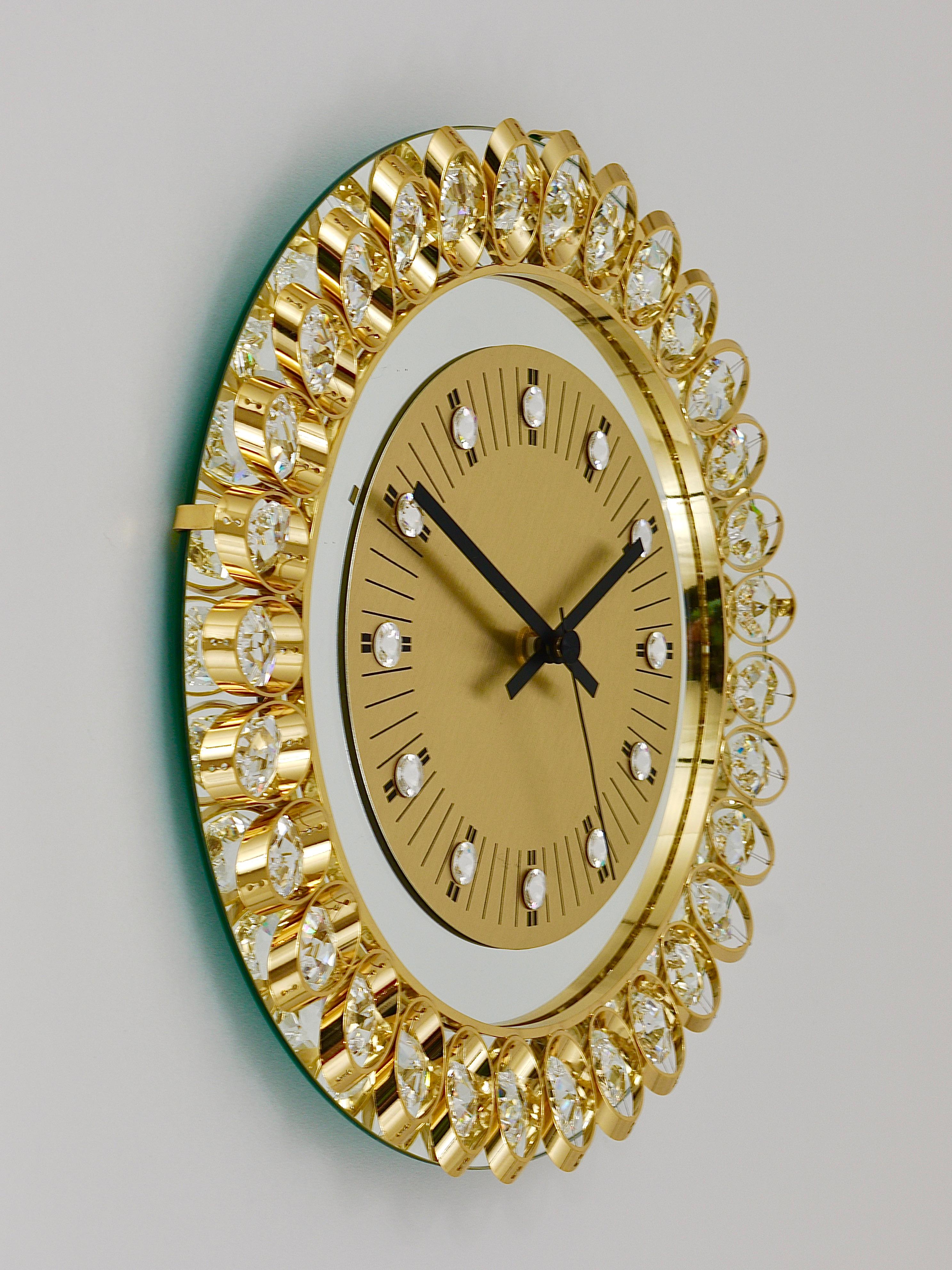 A beautiful round wall clock, executed in the 1970s by Junghans, Germany, in the style of Gaetano Sciolari or Palwa. The clocksface is made of mirror with a golden clocks face and nice crystal indices. The frame is made of gilt metal and decorated