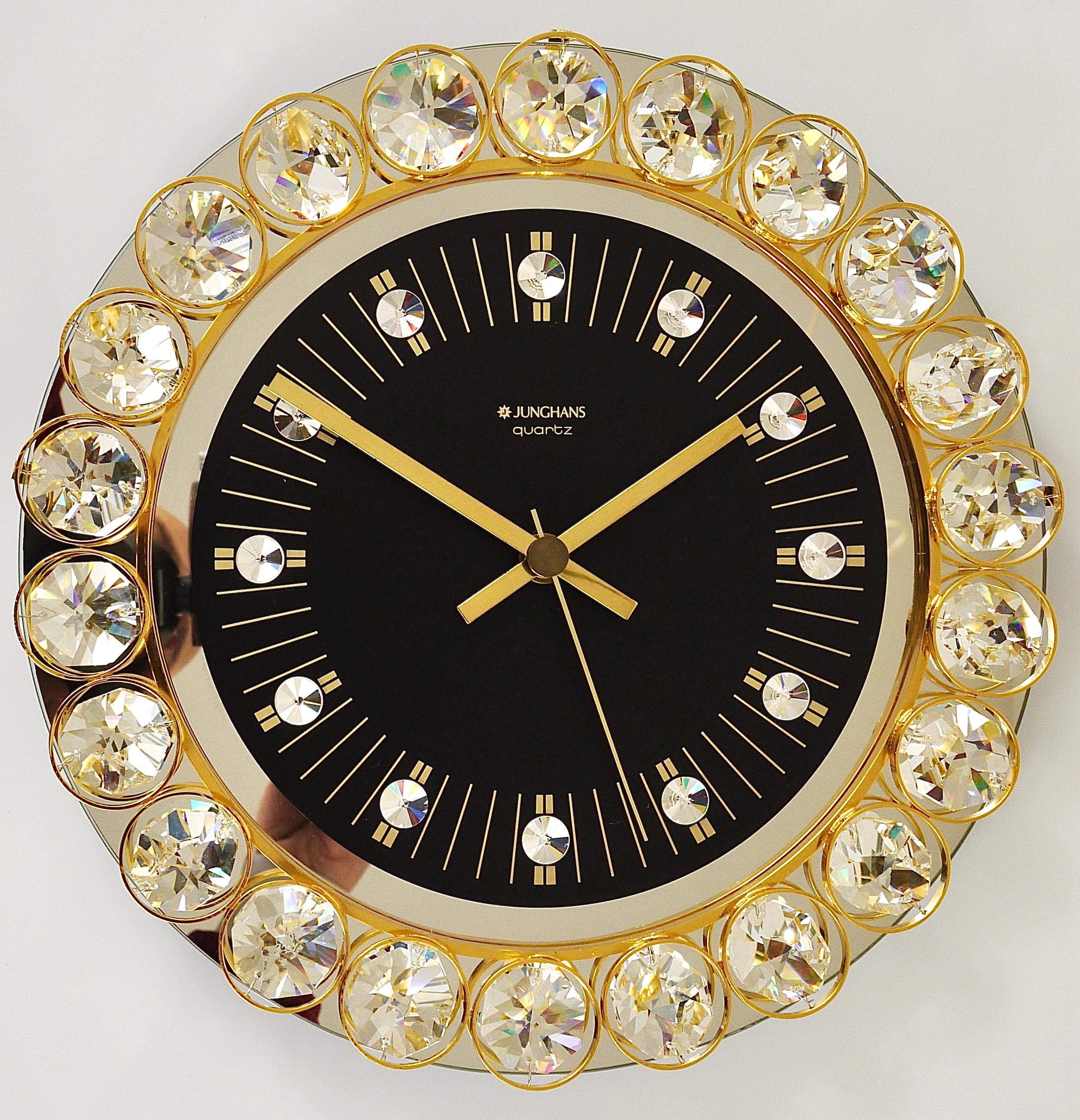 Une belle horloge murale ronde, exécutée dans les années 1970 par Junghans, Allemagne, dans le style de Gaetano Sciolari ou Palwa. La face de l'horloge est en verre miroir avec un cadran noir et de beaux index en cristal. Le cadre est en métal doré