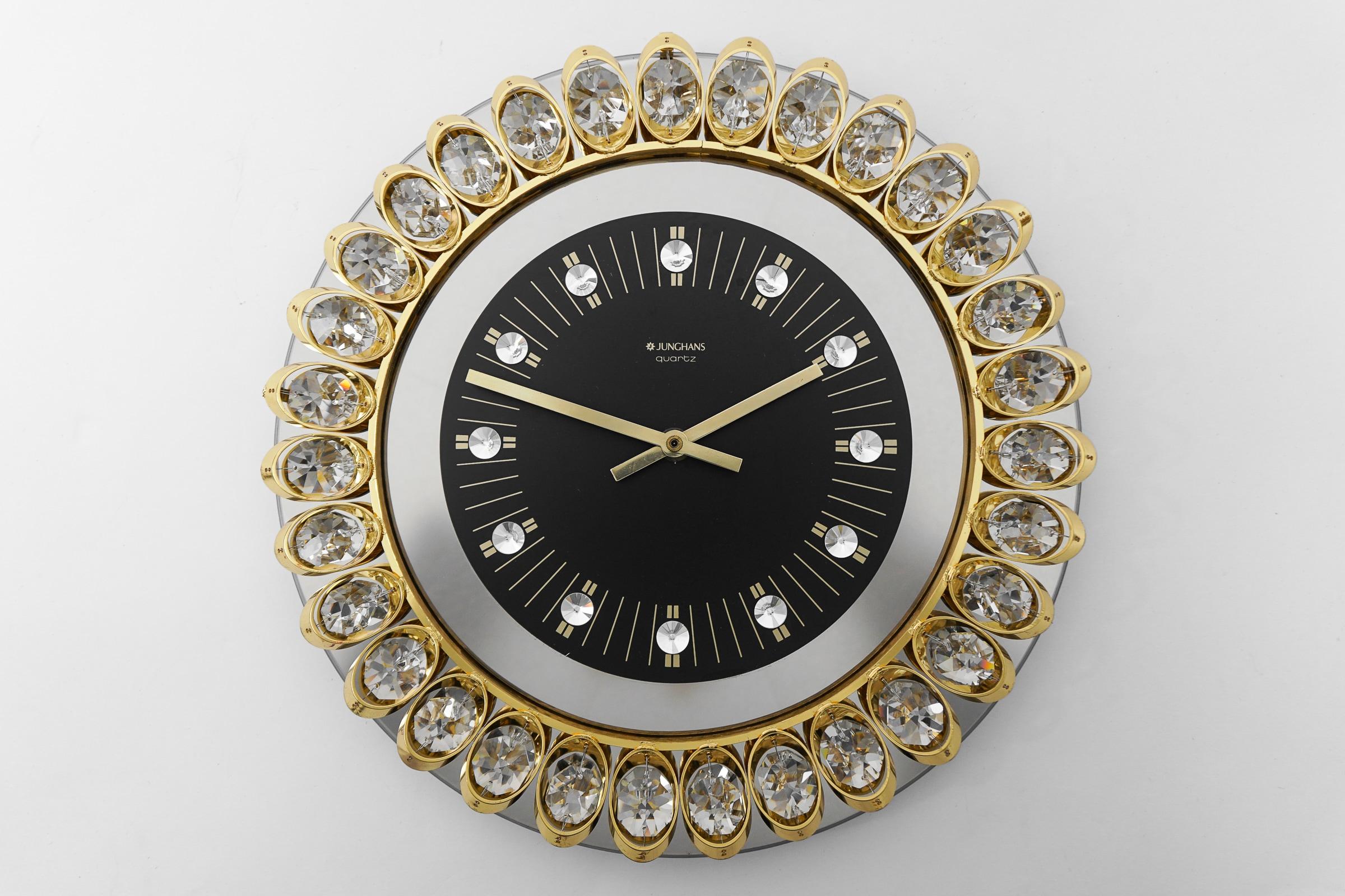 A beautiful round wall clock, executed in the 1970s by Junghans, Germany, in the style of Gaetano Sciolari or Palwa.

 The clock is made of mirror glass with a black clocks face and nice crystal indices. The frame is made of gilt metal and