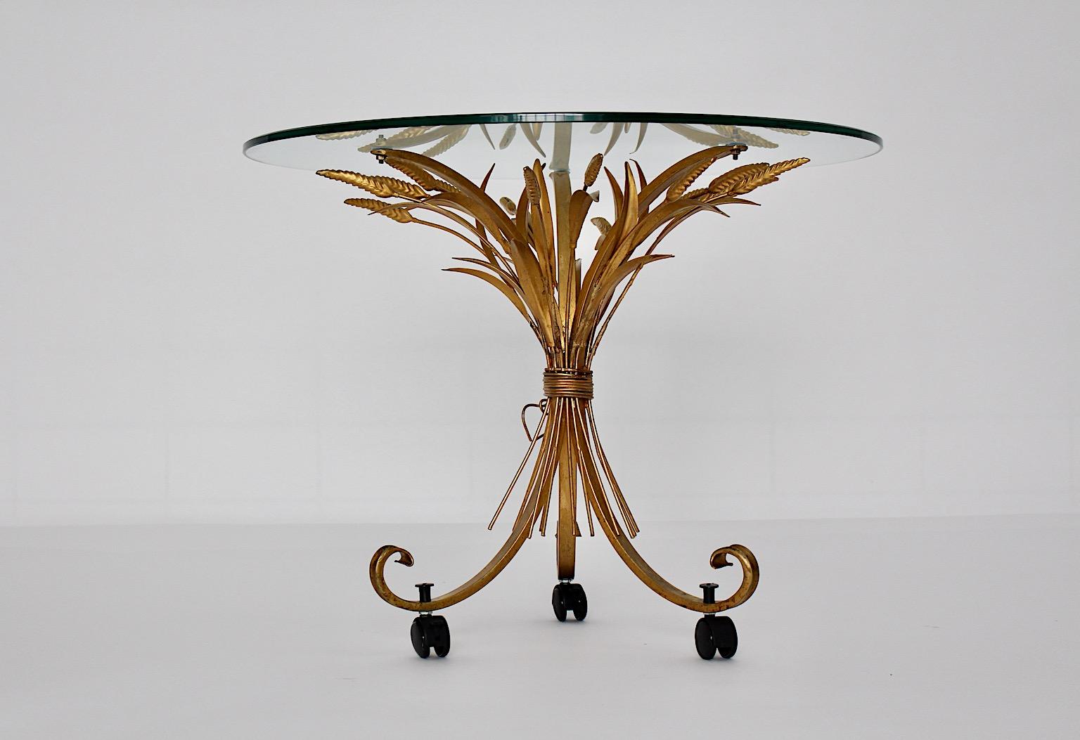 Table basse ou table d'appoint vintage en métal doré de style Hollywood Regency conçue dans les années 1970 en France.
Étonnante table basse avec une base ressemblant à une grappe de blé avec trois roues noires en bas et un plateau en verre