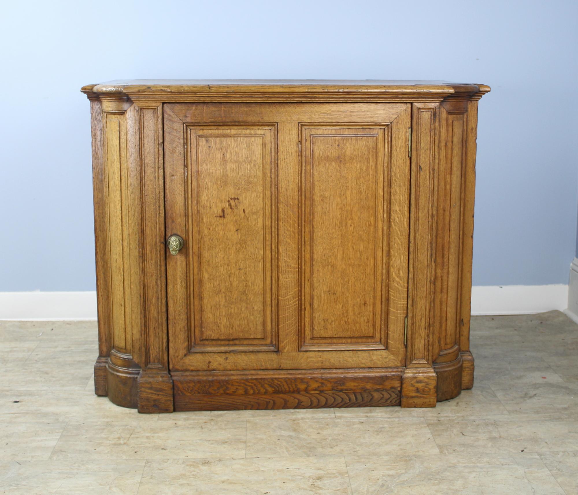A splendid oak cabinet with good mouldings, inset panels and a detailed plinth. Fine decorative piecework at the corners. Generously proportioned with a deep, clean cupboard and a single non-adjustable shelf. Brass knob closes the door snugly. A