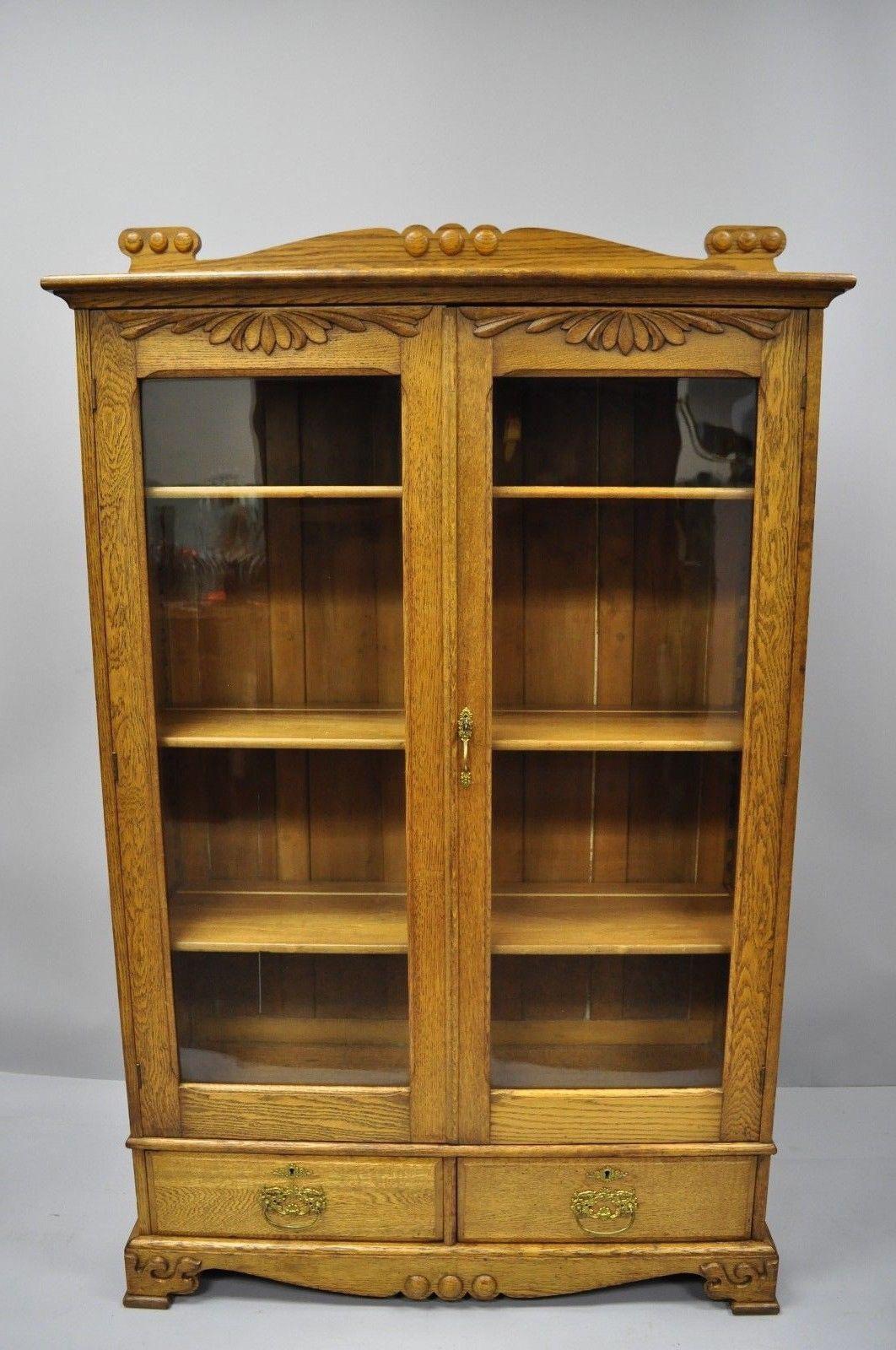 Antique golden oak Victorian two-door China cabinet bookcase with two dovetail drawers. Item features solid wood construction, beautiful oakwood grain, nicely carved details, two glass swing doors, working lock and key, plate groves, two dovetailed