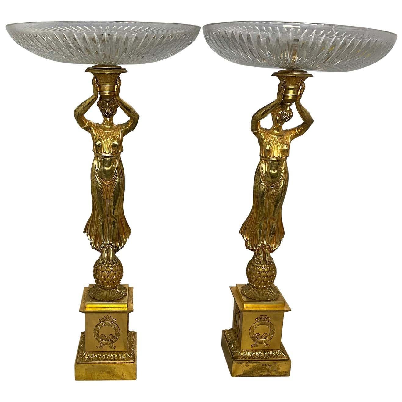 A pair of allegorical French Tazzas with cut crystal bowls suspended by Aphrodite figurative ladies, and standing on pedestal bases with detailed Empire ormolu wreaths on the walls of the plinths. Perfect for holding fruit or sweets. 20th