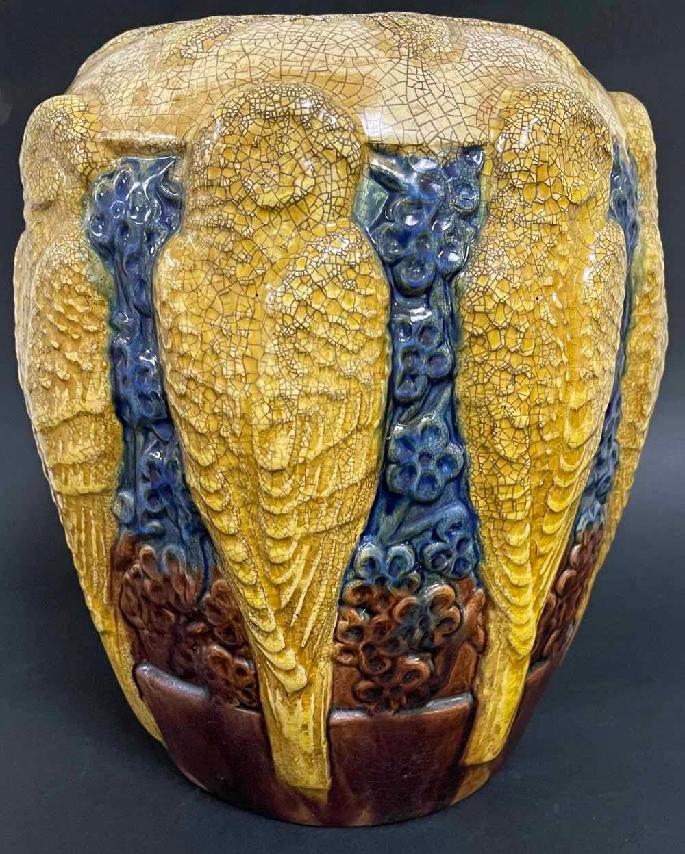 This large and striking vase -- the first example we have seen -- depicts a frieze-like line of golden parakeets or small parrots arrayed against a deep blue ground of flower forms.  The relief is high and bold, and the glazes are further enriched