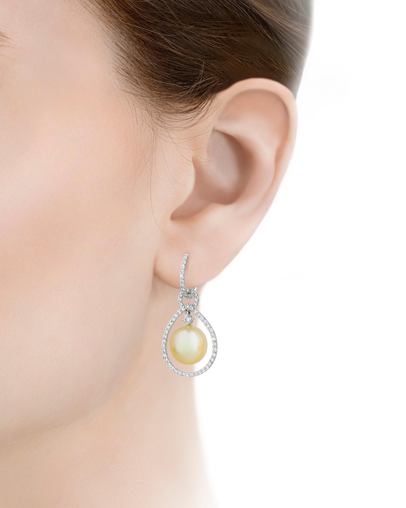 Two golden pearls dangle at the center of these elegant teardrop earrings. Perfectly matched in size and color, this exceptionally rare pair measure an impressive 11mm. Dozens of brilliant white, pavé-cut diamonds totaling 1.15 carats encircle the