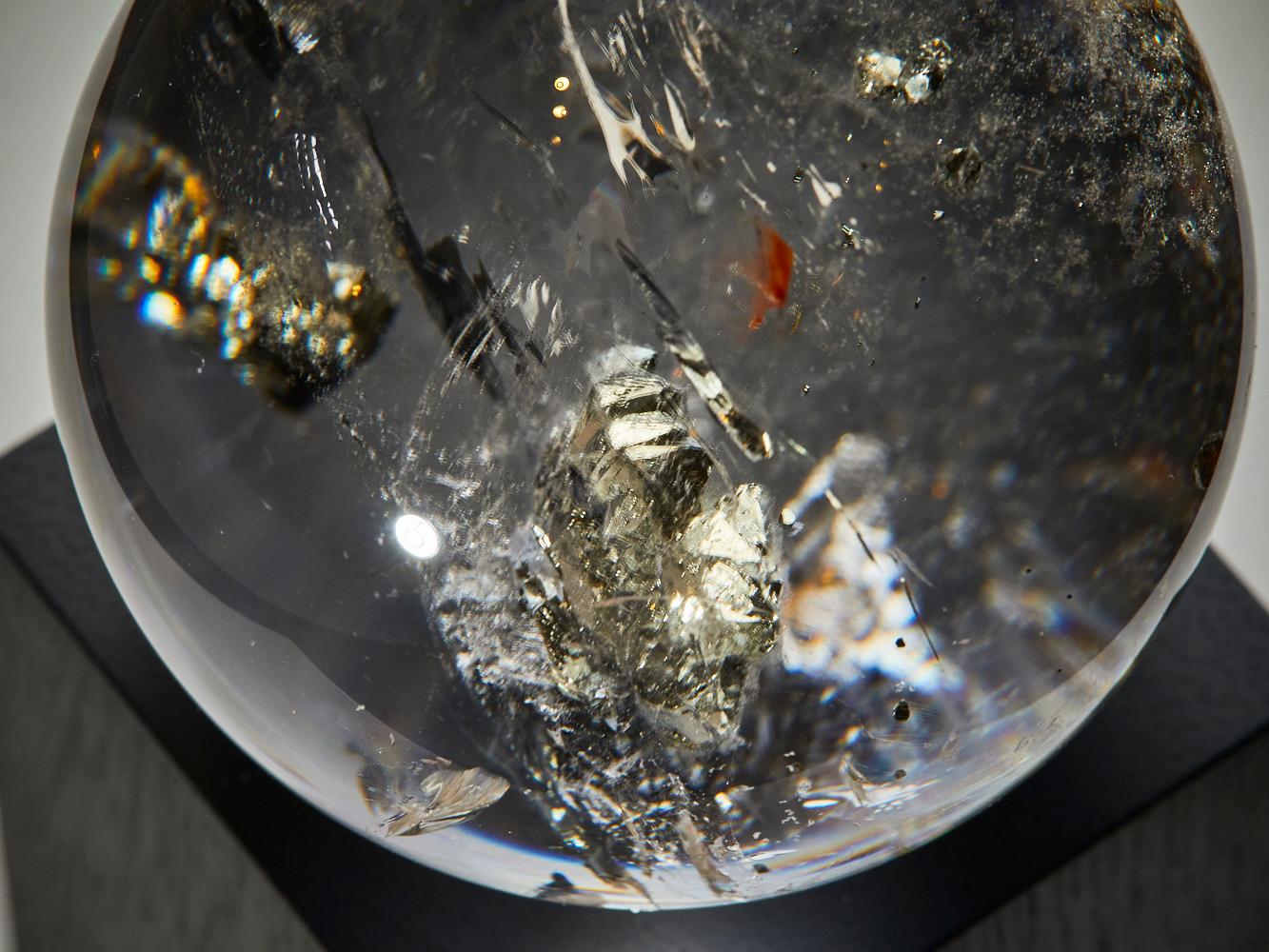 Cette sphère de quartz lumineuse provenant du Brésil est ornée de pyrite dorée brillante
inclusions suspendues dans son intérieur cristallin. Chaque fleur métallique attire la lumière comme des étoiles miniatures, flottant dans un paysage serein et