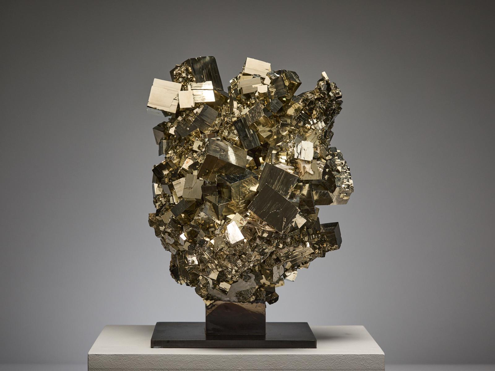 An extraordinary sculptural formation of golden pyrite from the famous Huanzala Mine in Ancash, Peru, composed of perfect interlocking cubes of varying sizes that appear almost hand-crafted. The arrangement creates a striking, three-dimensional