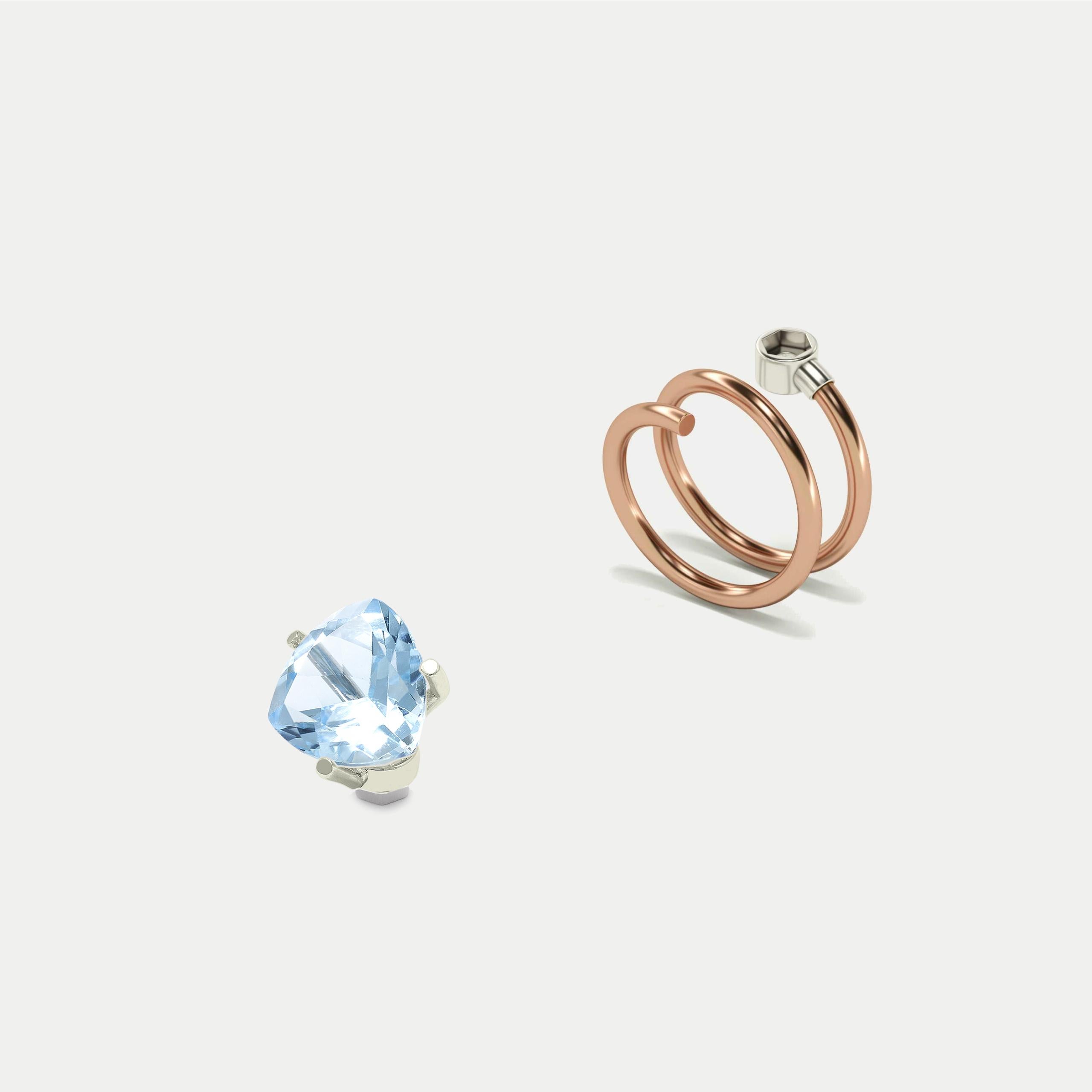 Blue Sky Topaz White, trillion cut, White Gold head, 18K
Elastic Spiral Rose Gold Ring, 18K

You can put and take on Blue Sky Topaz in the ring. 
This is only possible with a surgical steel mechanism. Surgical steel is more resistant to mechanical