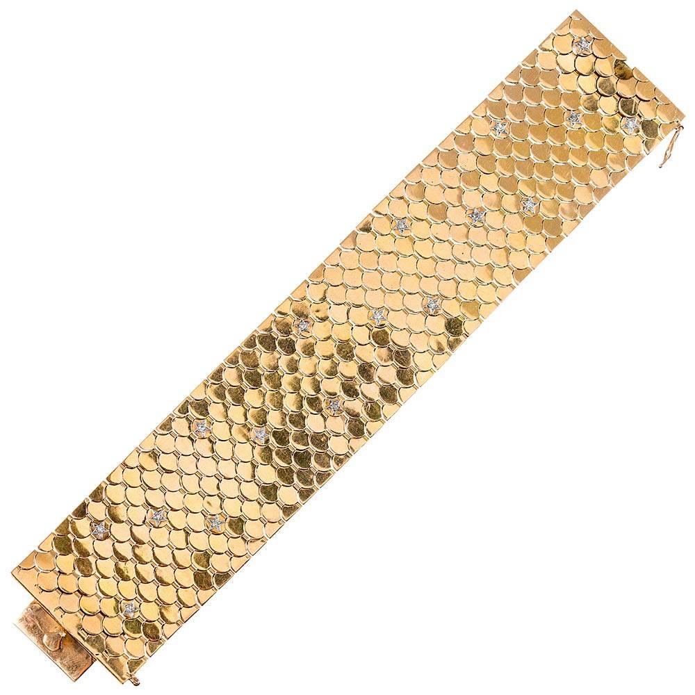 Overlapping discs of 18 karat yellow gold create a lacertilian affect. The design is enhanced by tiny platinum stars, each set with a diamond solitaire, peppered about. The bracelet measures 7 3/8 inches long and 1 ½ inches wide. Turn it over and