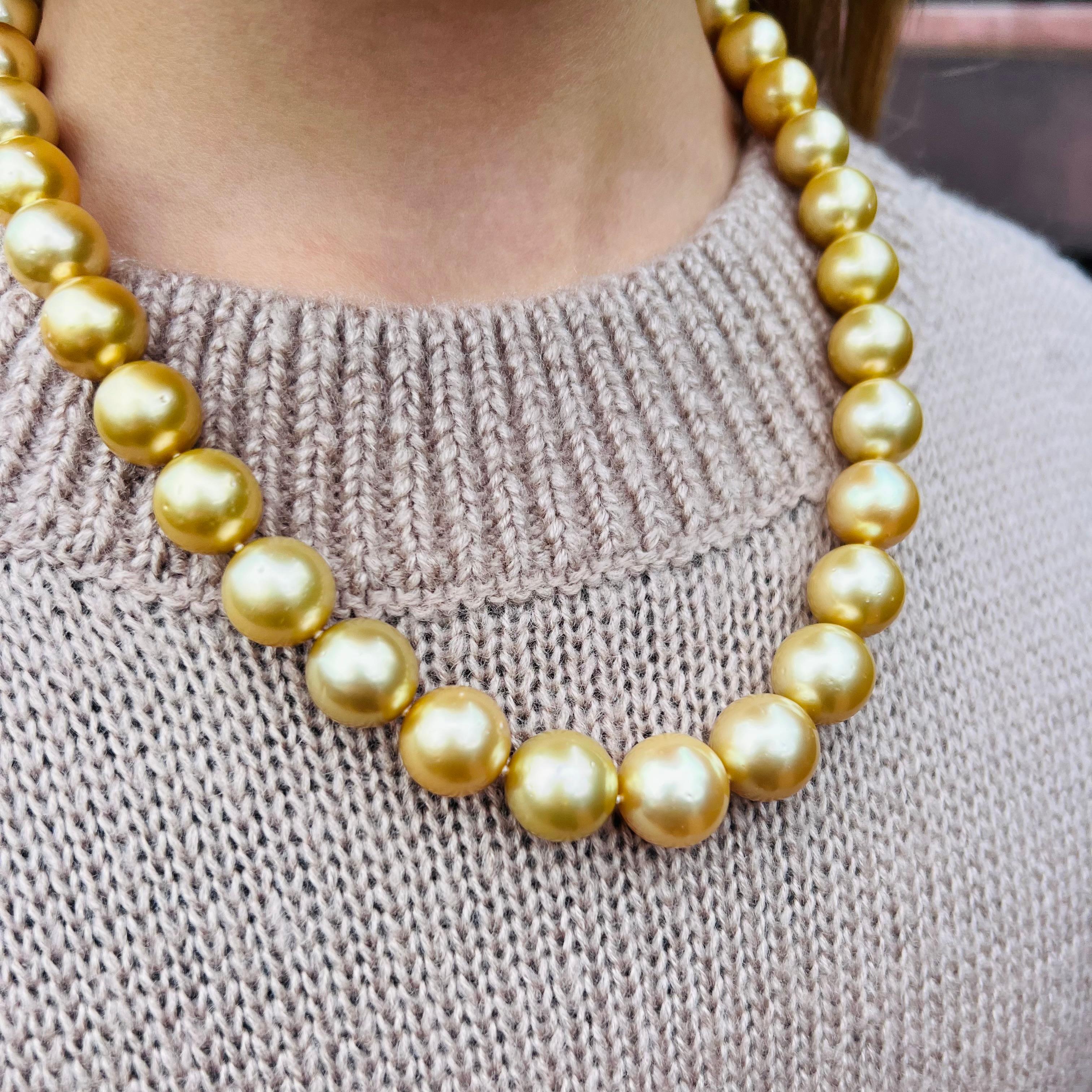 Kissed by the sun! This strand of highly lustrous golden South Sea cultured pearls is composed of 25 pearls measuring from 13.63 to 11.0 mm, and finished with a unique, polished clasp. The necklace weighs 92.8 grams, and is 18 in. long. A golden