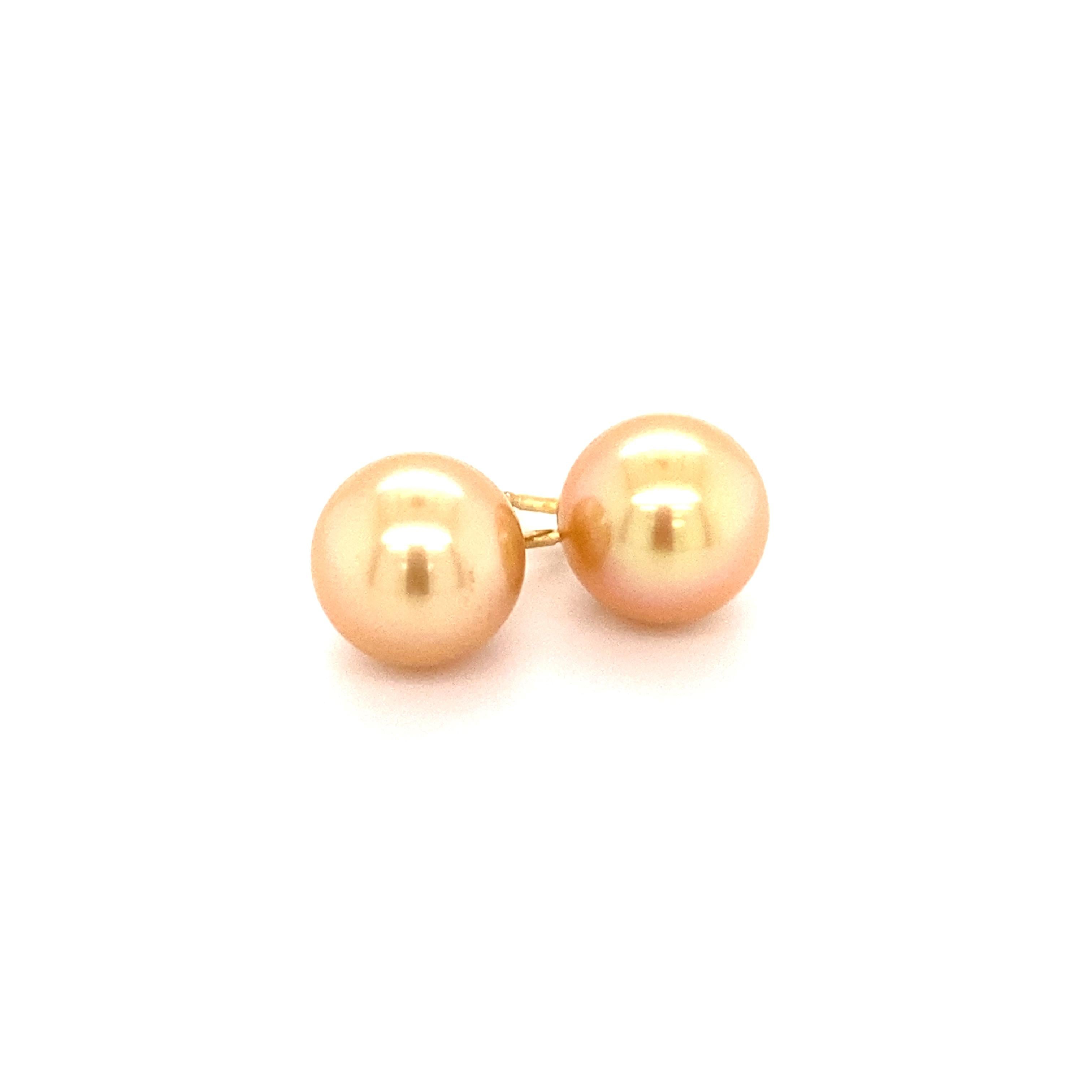 Cette paire de boucles d'oreilles intemporelles est sertie de deux fabuleuses perles de culture des mers du Sud, rondes et dorées, de 11,5 mm de diamètre. Les perles de culture ont non seulement une couleur chaude et rayonnante, mais aussi un très