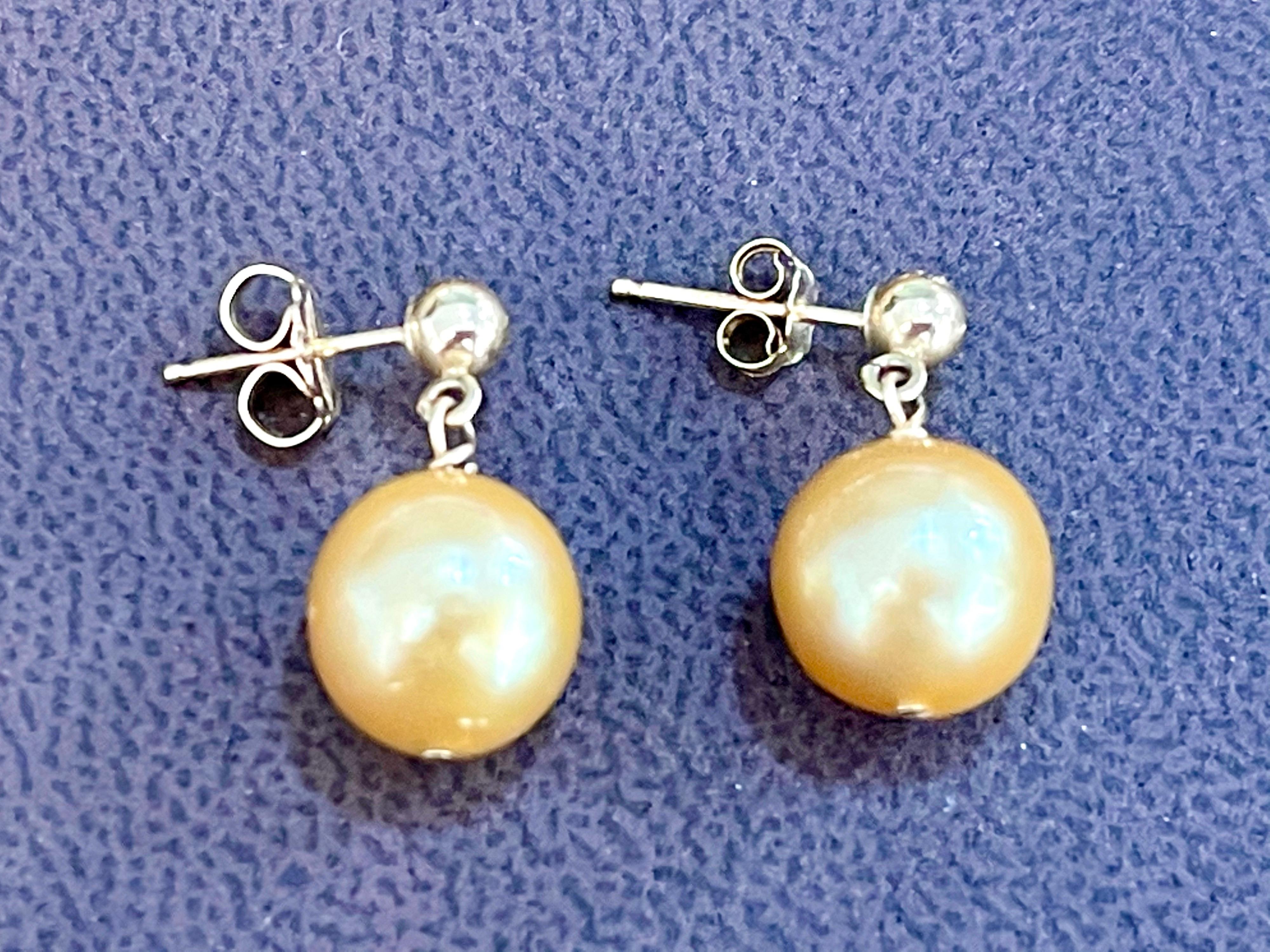 
10 MM Golden South Sea  Pearl Dangling Earrings 14 Karat Yellow Gold
All pearls are absolutely clean with no blemishes .Approximately 10 mm 
small gold stud at the top of the earring which sits on ear lobe and pearl dangle from it.
it is a post