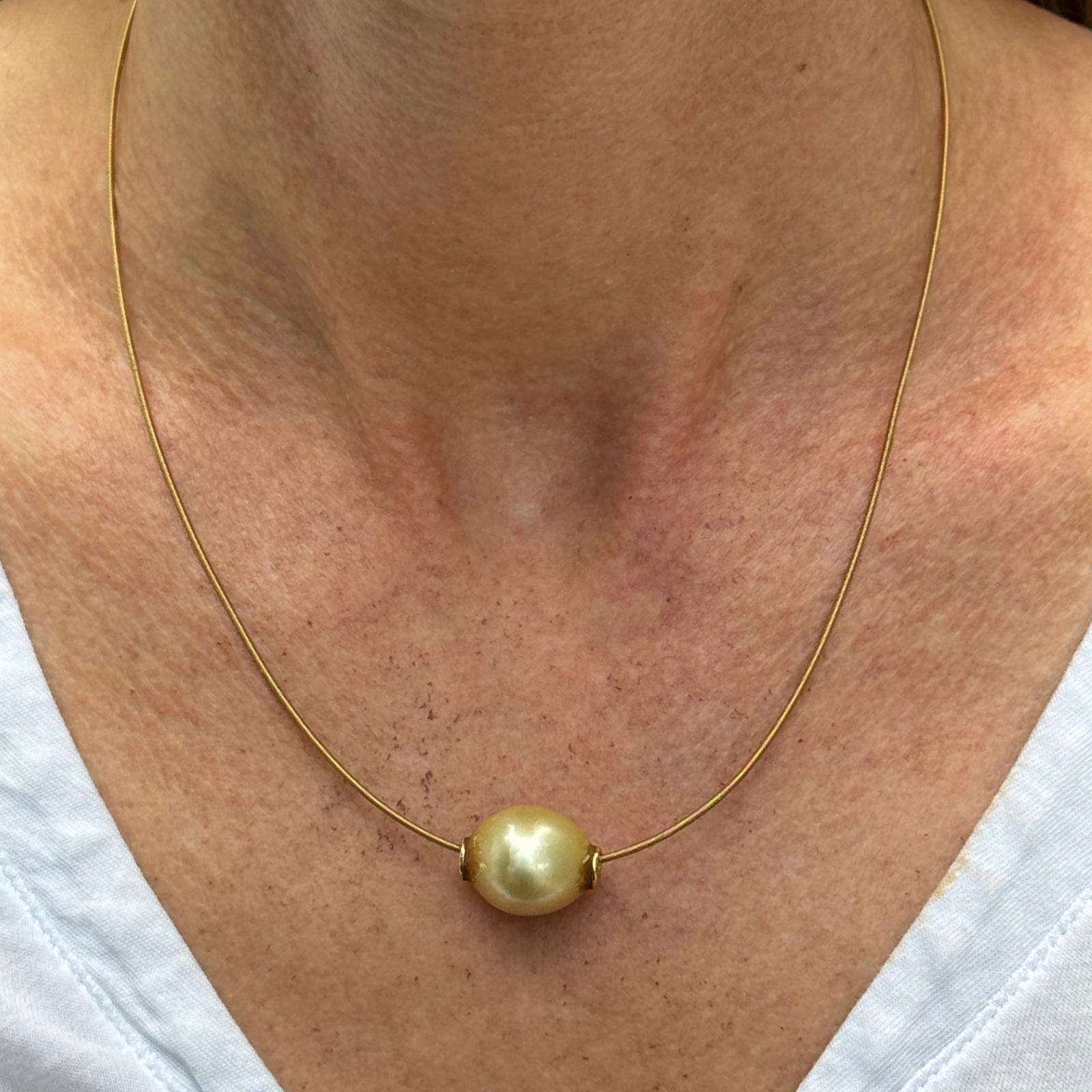 The Golden South Sea Pearl Solitaire 18 Karat Yellow Gold Snake Chain Necklace is a modern and elegant piece of jewelry. Featuring a single 13.2mm lustrous golden South Sea pearl, this necklace is set on a sleek 18 karat yellow gold snake chain