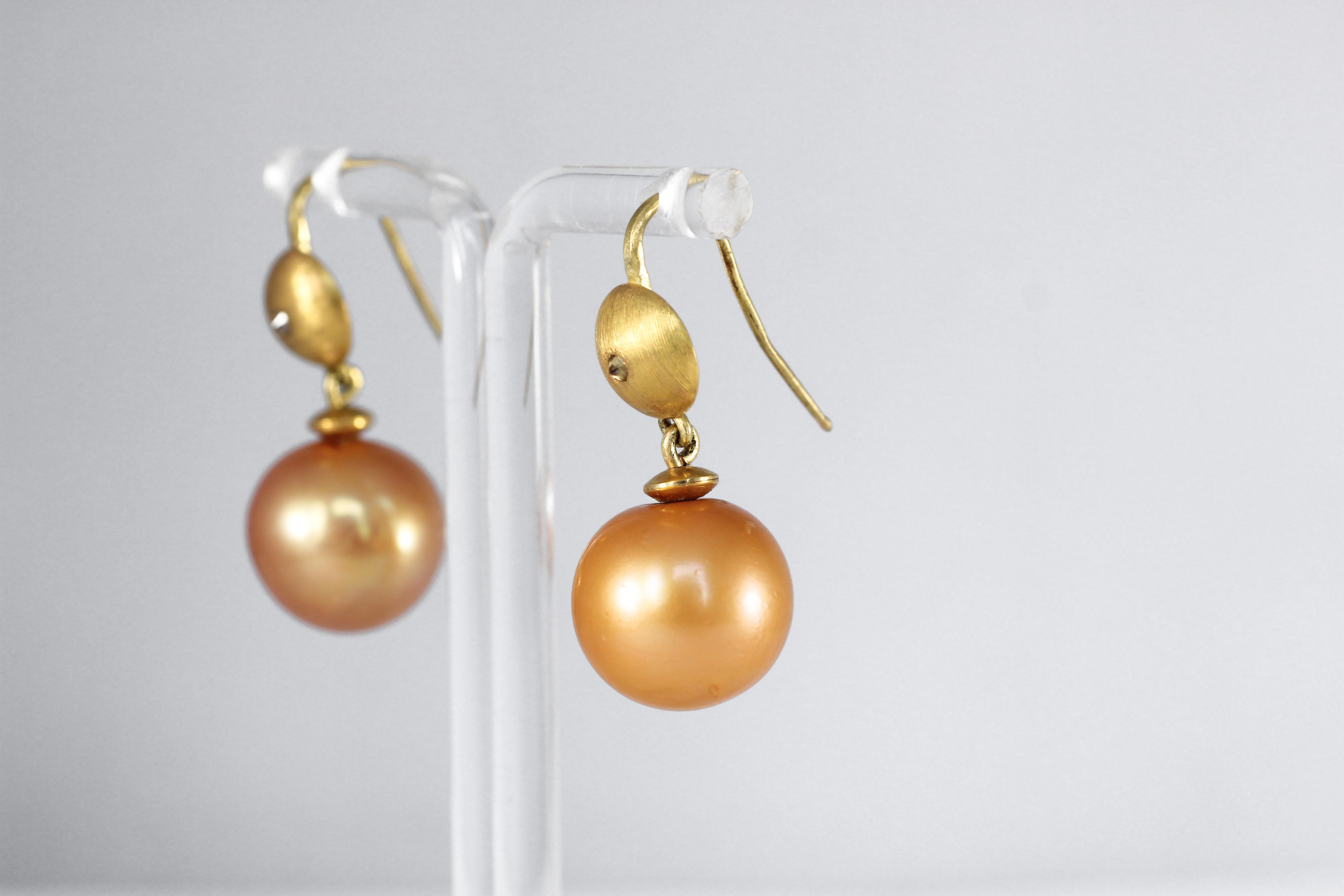 Goldene Eve-Tropfen-Ohrringe. Diese eleganten, modernen Ohrringe aus 21-karätigem Gold sind eine Aktualisierung eines Klassikers. Das Wunder der Natur, eine 15 mm große, gold-orangefarbene Südseeperle, spiegelt sich in einer eingravierten goldenen