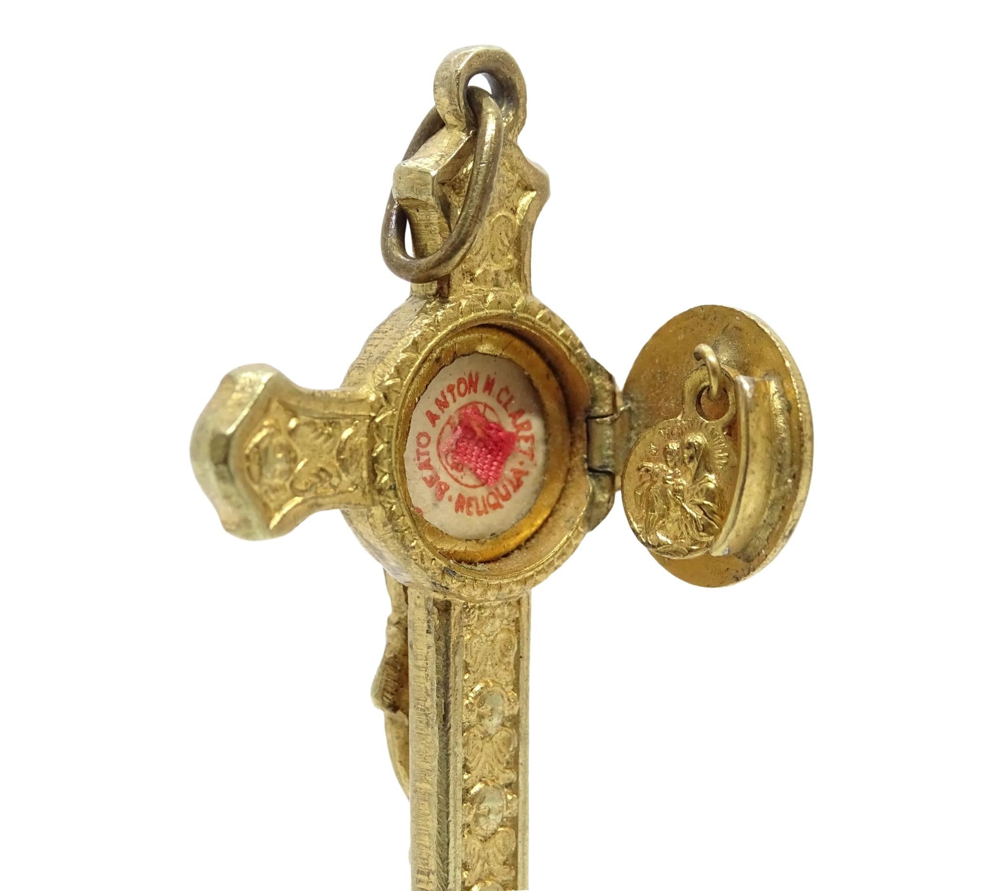 This golden crucifix-shaped reliquary pendant is dedicated to the Catalan Saint Antonio María Claret. This Latin cross with circular finials features a crucified Christ in relief. The arms of the cross are decorated with seraphim, both on the front