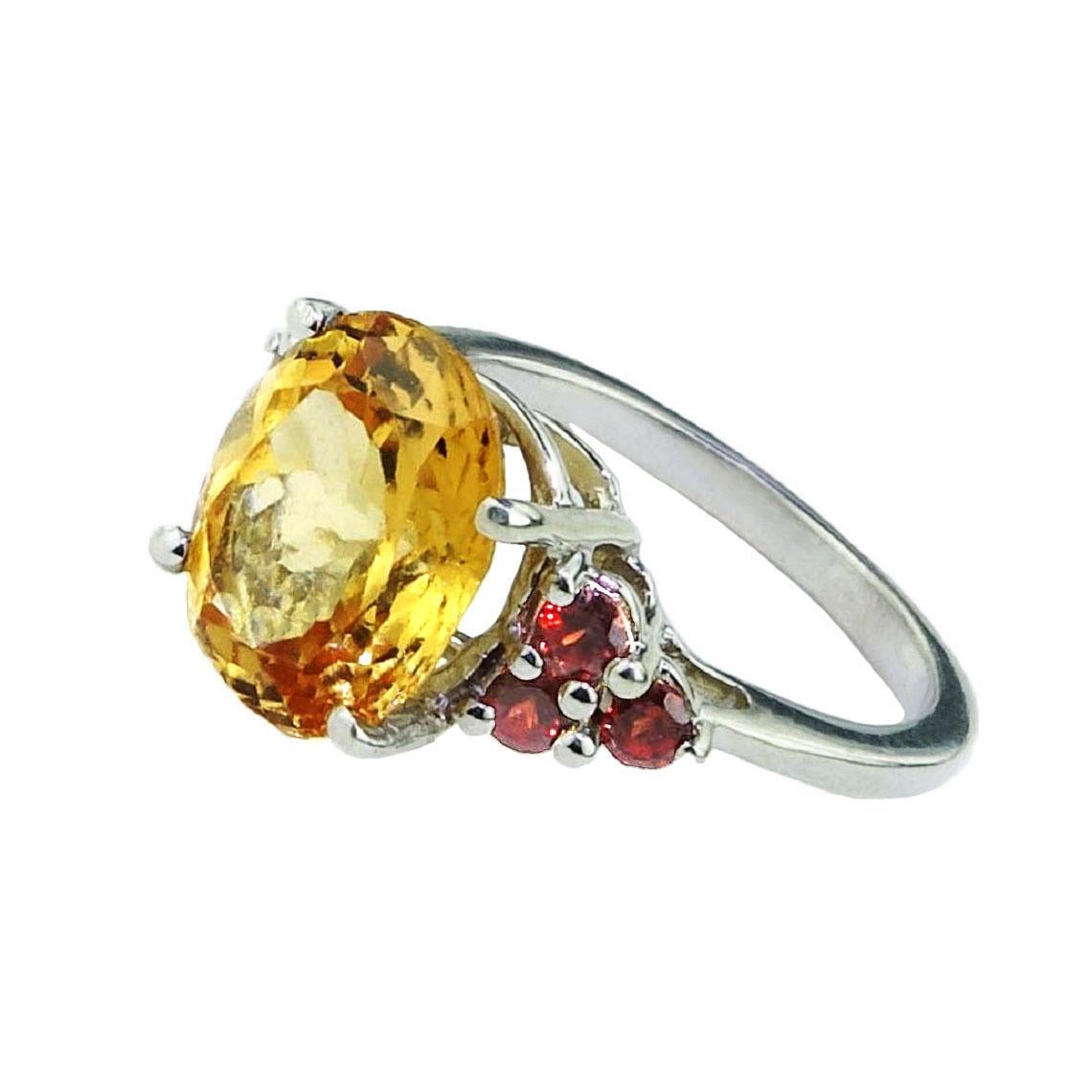 Wow!  Great cocktail ring, wear this stunner for that great feeling of a one of a kind personal ring.  Sterling Silver Ring with brilliant cut, oval Golden Tourmaline (approx 4.95 ct) accented with six red garnets with a total weight of 0.42 ct.