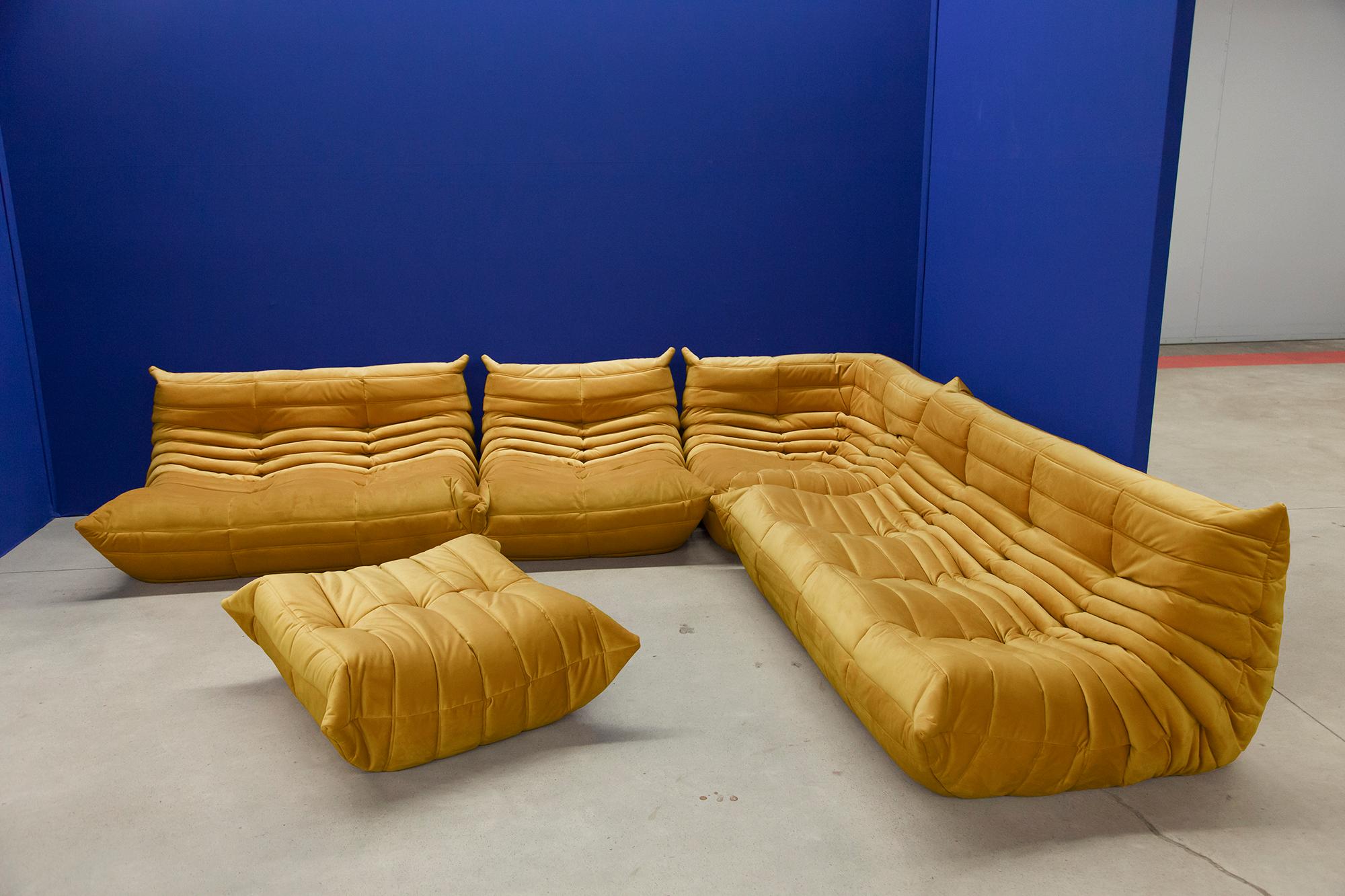This Togo living room set was designed by Michel Ducaroy in 1974 and was manufactured by Ligne Roset in France. Each piece has the original Ligne Roset logo and genuine bottom. It has been reupholstered in genuine high quality golden/yellow velvet