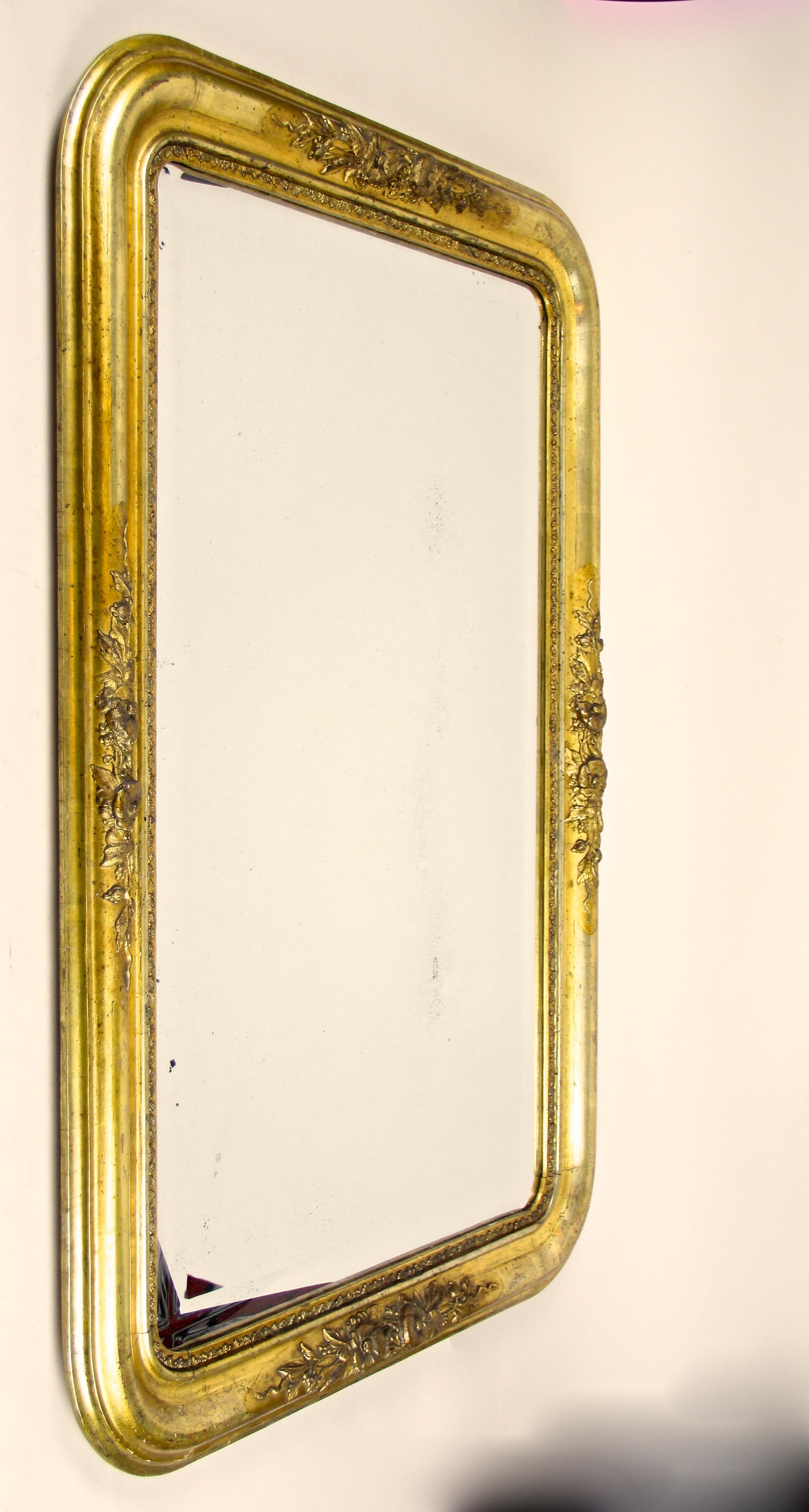 Precious Golden Biedermeier wall mirror from the famous period circa 1840 in Austria. Standing out with beautiful floral stucco works, silver plated half rods and rounded corners, this charming frame was restored by our experts while taking greatest