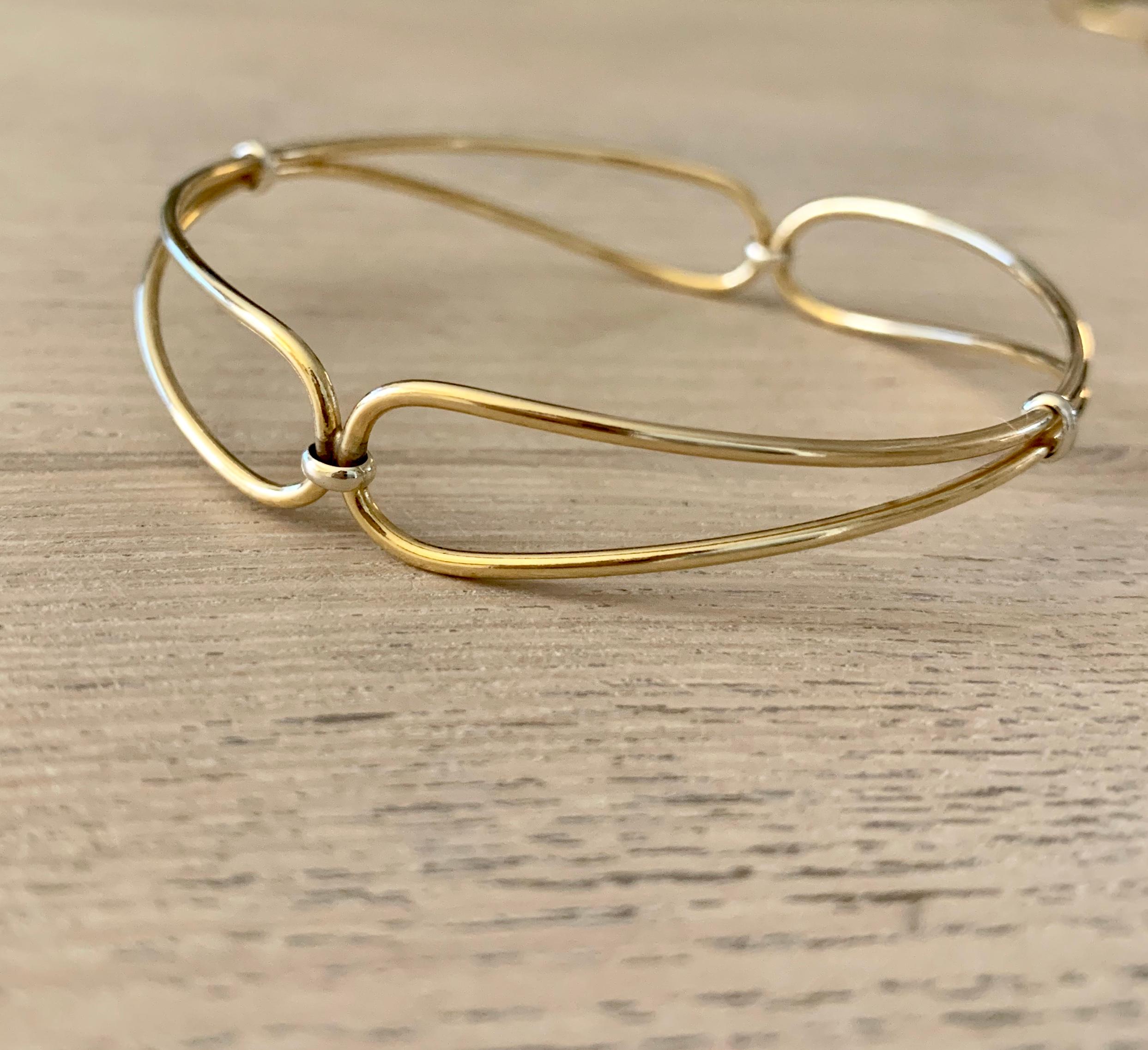 This stunning solid gold bangle is a timeless classic - modern and delicate to be worn on any occasion by its self of layered with other bangles.

- 9 karat yellow with white gold detailing
- Gold wire - each 1.5mm thick
- Diameter 65mm
- 8.40