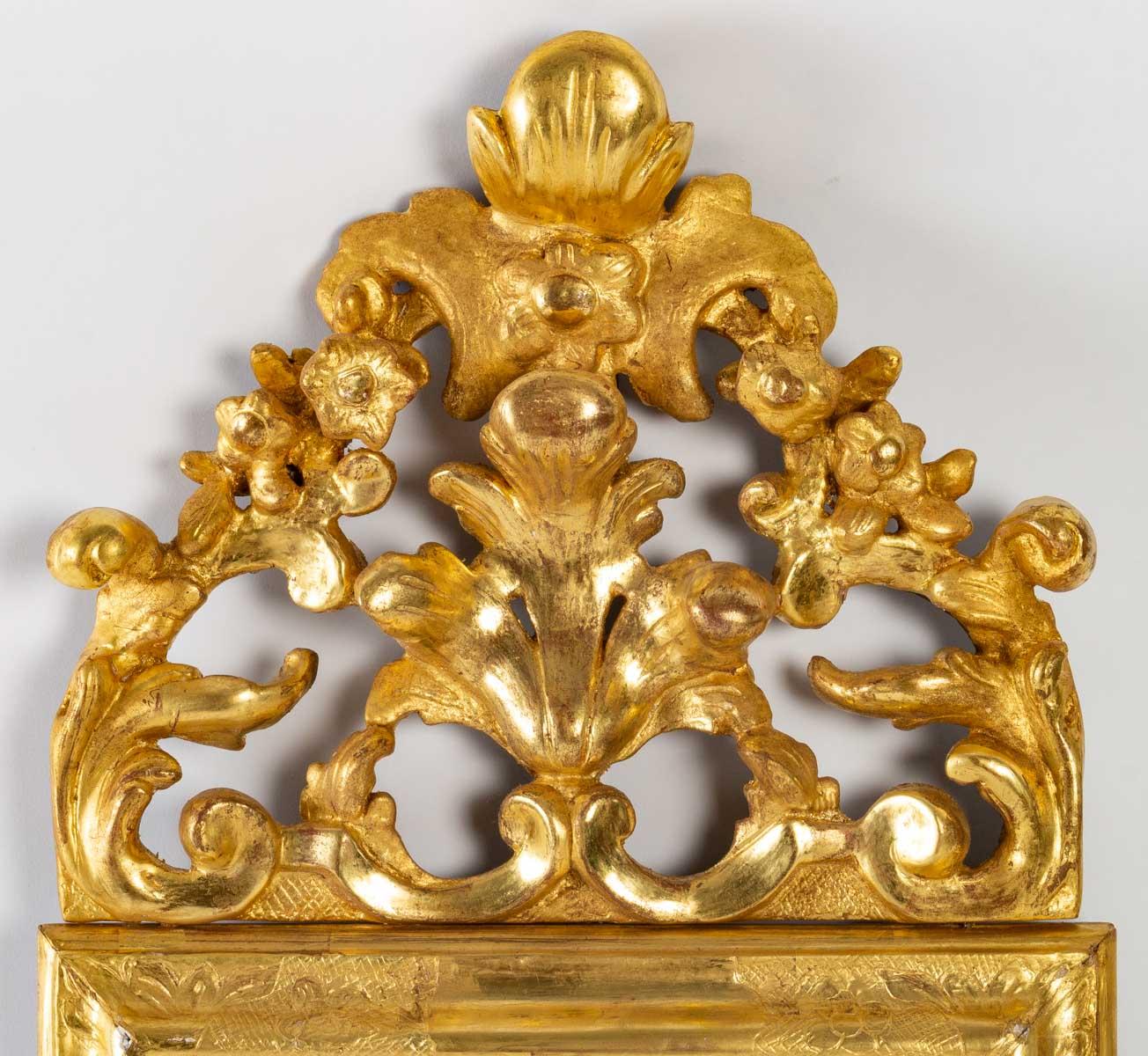 Lovely little mirror in carved wood, gilded with 24 carat gold leaf, Louis XV period, old mercury ice. Its pediment is openwork with patterns of shells and acanthus leaves, and its sober frame presents a refined decoration only at the angles as well