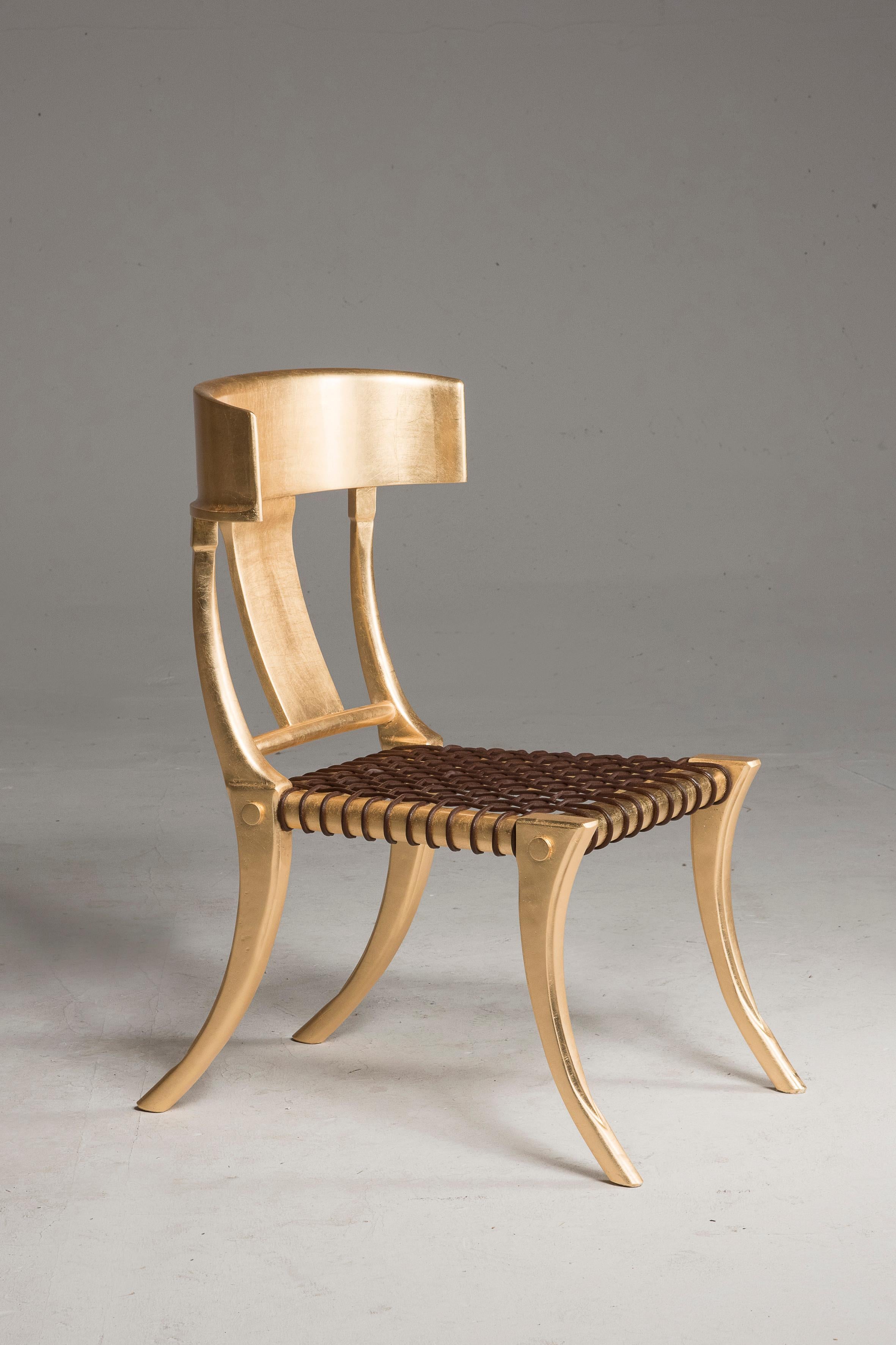 Klismos customizable dining chairs with saber legs, golden lacquered wood and black woven leather seats.

Available in other colors and upholstery. Italian artisanal production by Pescetta Home Decoration. Klismos are walnut wood chairs with deep