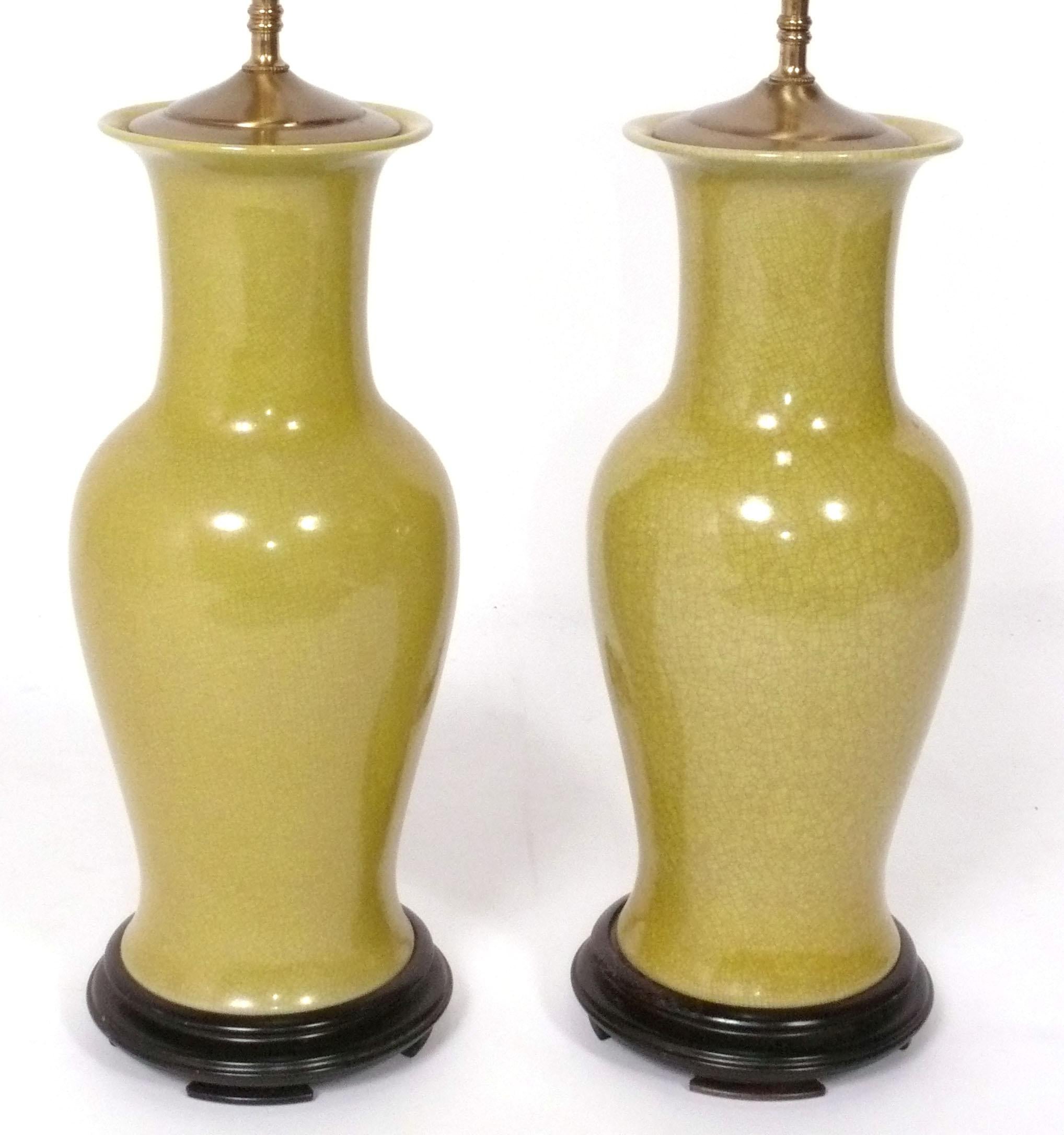 Elegant Goldenrod Yellow Chinoiserie Ceramic Lamps, probably American, circa 1960s. Constructed of curvaceous goldenrod yellow vases with a wonderful overall craquelure, with Asian inspired wood bases and brass caps. They have been rewired and are