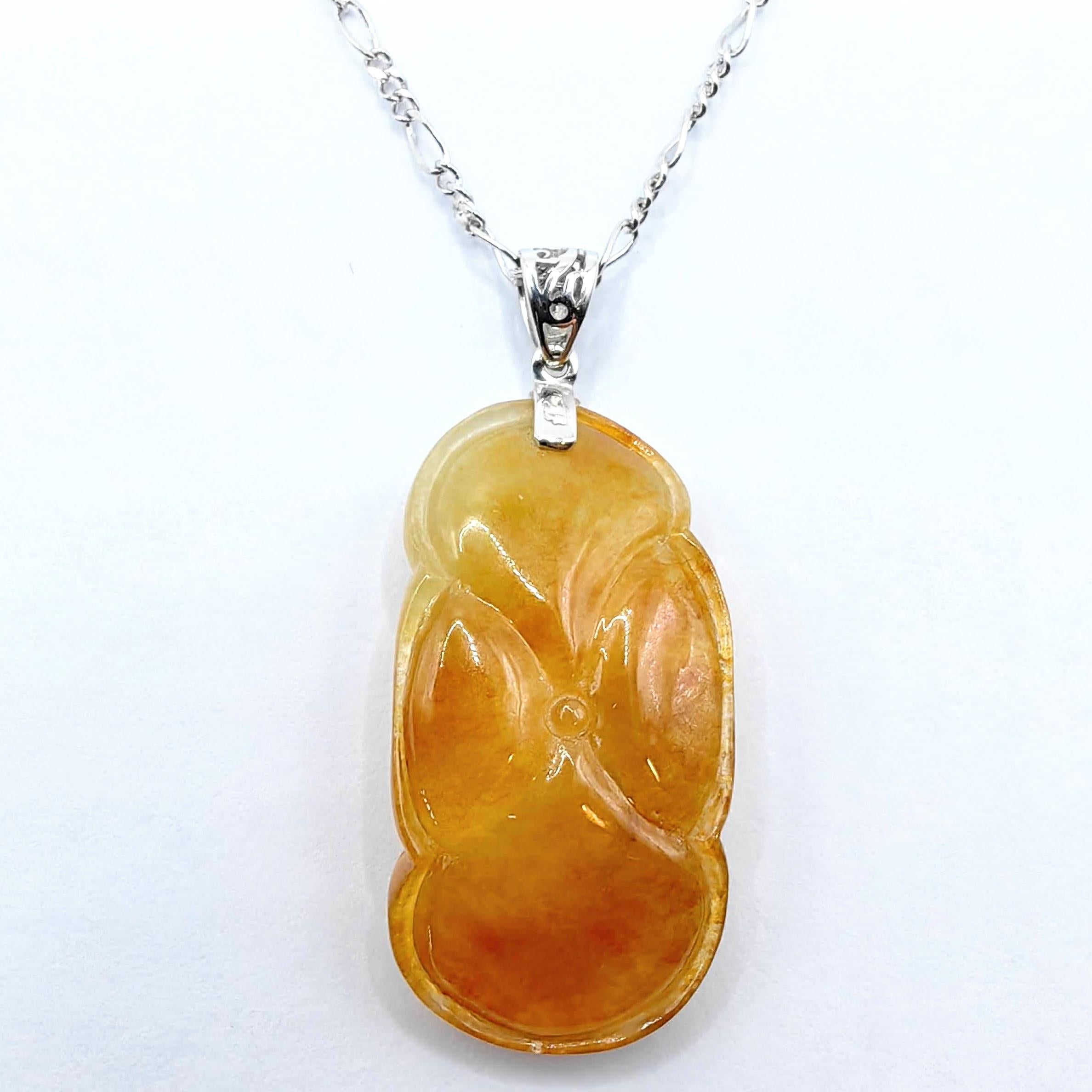 Discover the enchanting beauty and symbolic charm of this Goldfish in Pond Honey Amber Jadeite Jade Pendant, masterfully carved from a single piece of premium jadeite in the coveted Huang Fei (黄翡) variety. Elegantly set with an 18K white gold bail,