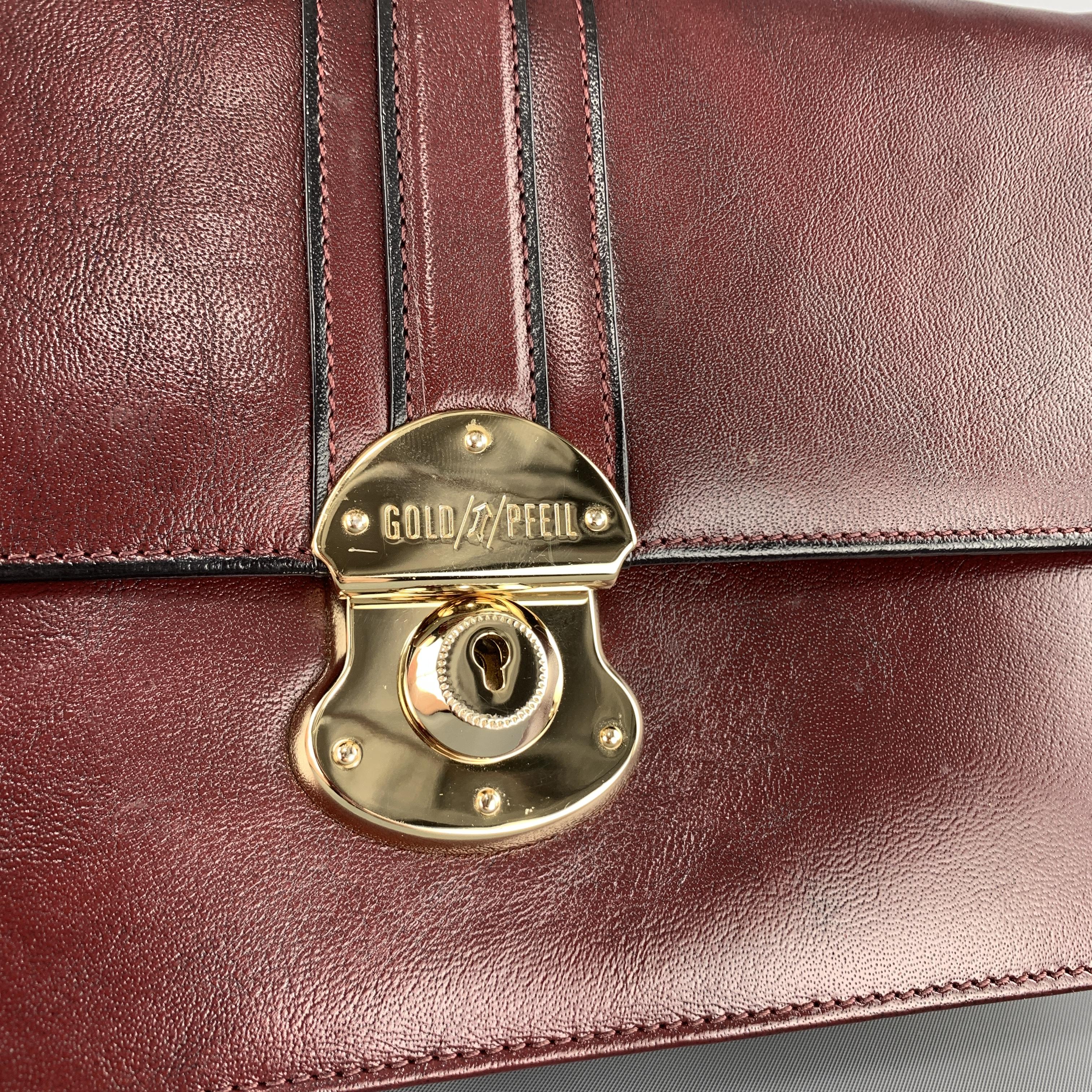 GOLDPFEIL mini briefcase clutch comes in burgundy leather with a flap top, gold tone lock closure, retractable side strap, and interior storage. 

Excellent Pre-Owned Condition.

Measurements:

Length: 9.75 in.
Width: 2 in.
Height: 6.5 in.