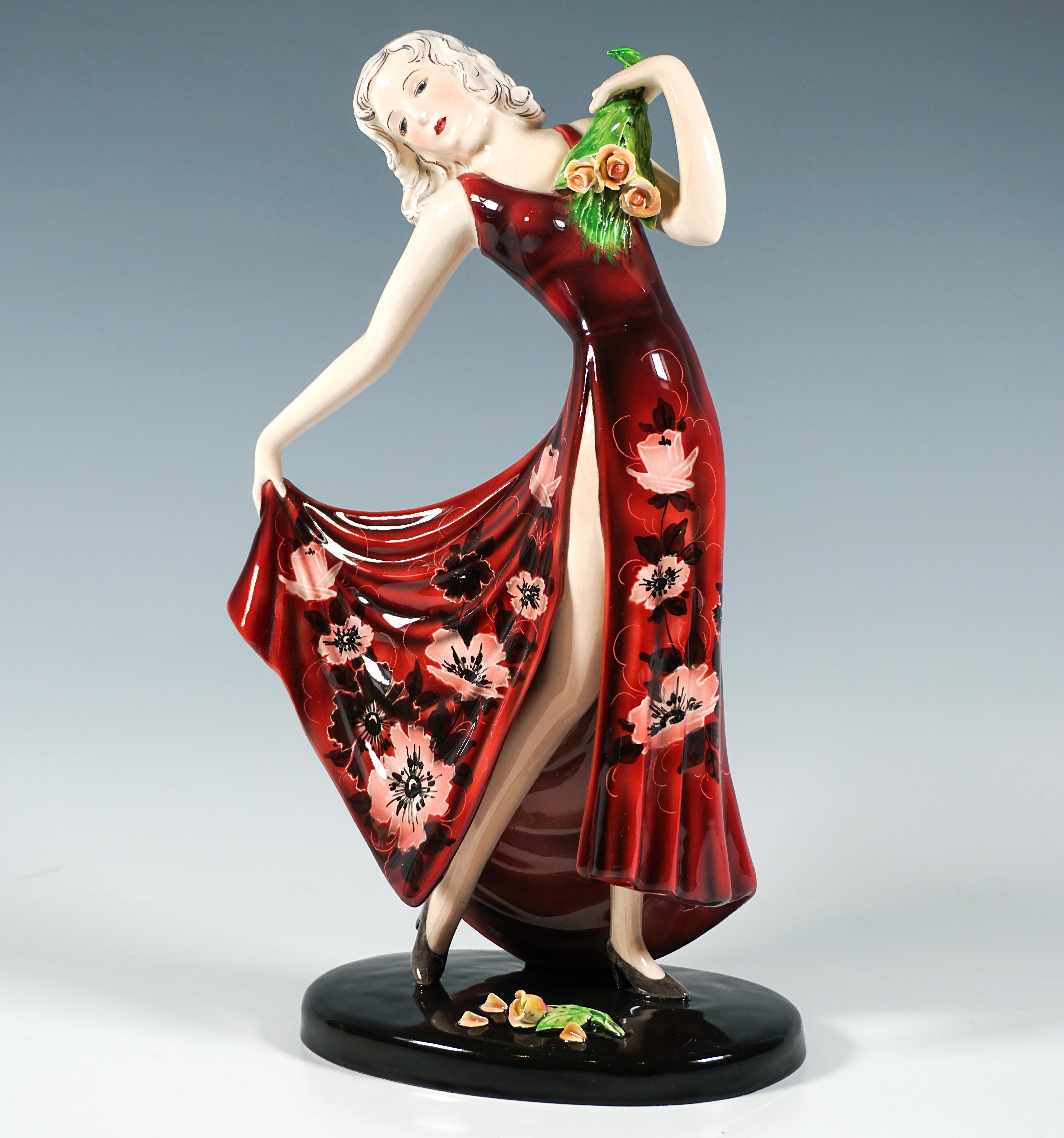 Una leggiadra ballerina con un lungo abito rosso scollato e a spacco alto con un motivo floreale all-over, con la testa inclinata a destra e lo sguardo rivolto verso il basso, la mano sinistra che appoggia sul petto un bouquet di rose rivolto verso