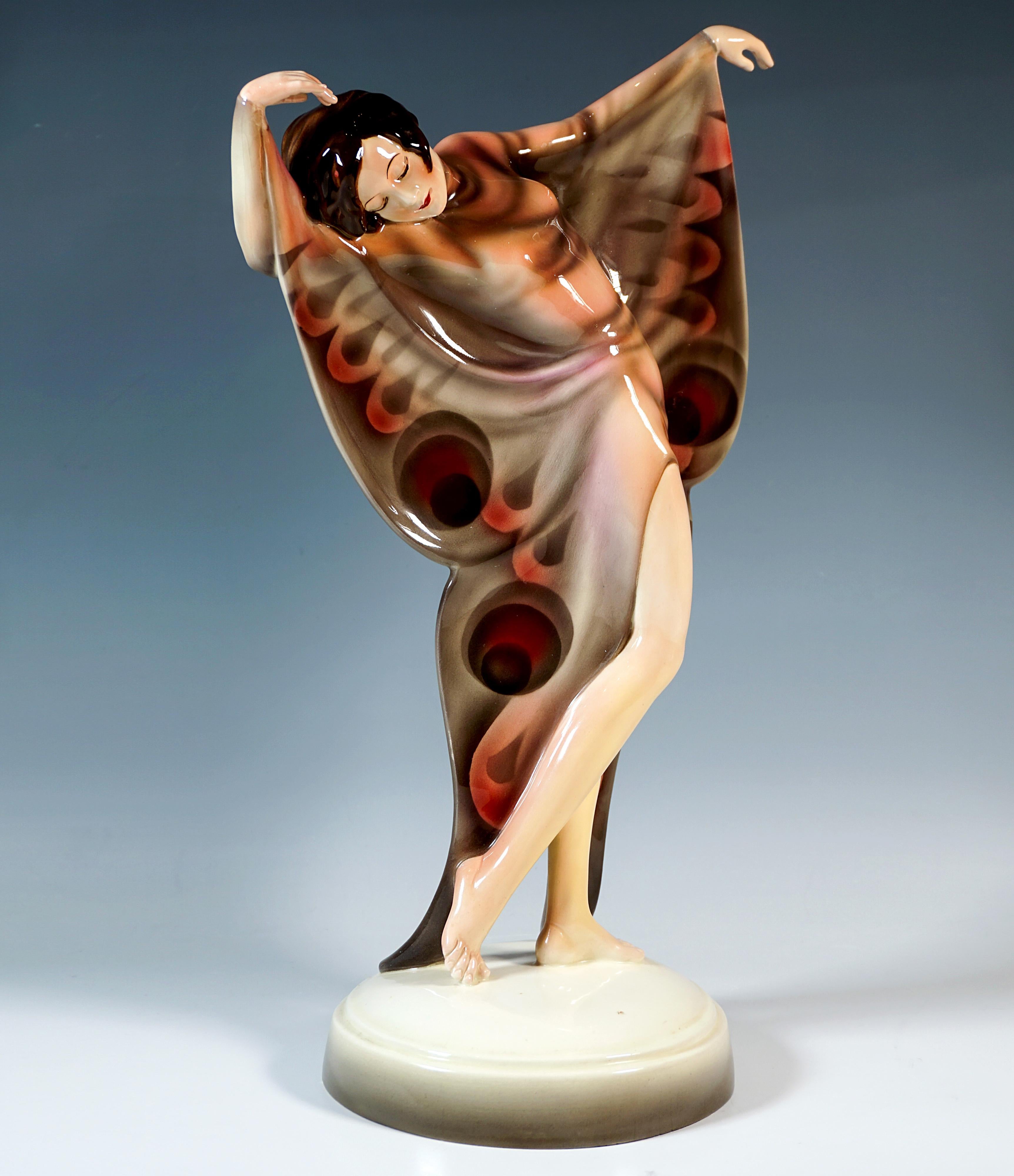 Excellente figurine en céramique avec une rare décotation des années 1930 :
La sculpture représente une danseuse en costume de papillon. Debout, les bras levés et la tête penchée sur le côté, elle effectue un léger mouvement de torsion. Le costume