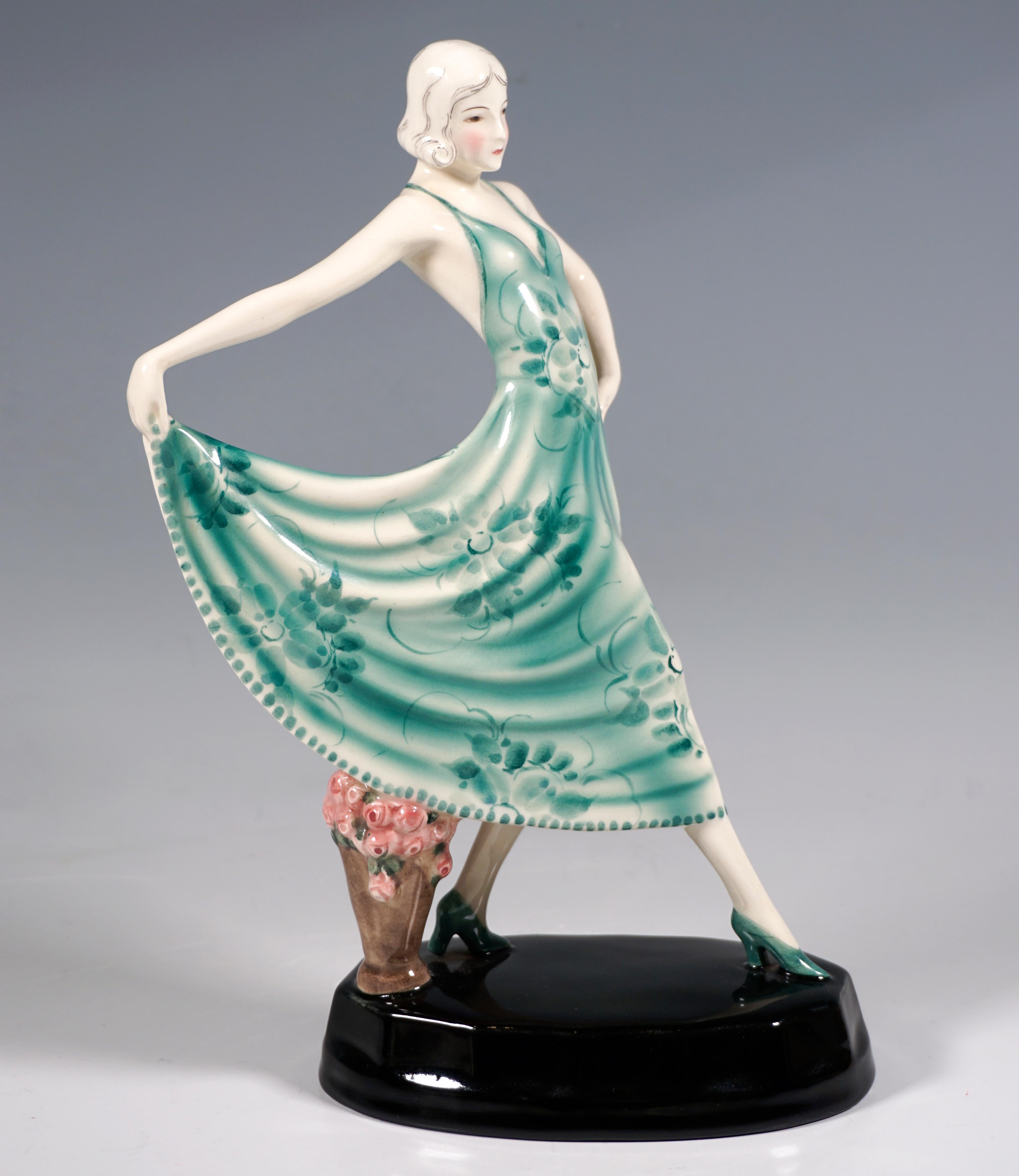 Delicate Goldscheider Art Ceramics Figurine of The 1920s:
Actress Lilian Harvey with chin-length, light hair as a striding dancer, holding up the hem of her low-cut, green strappy dress with floral decoration with her right hand stretched straight