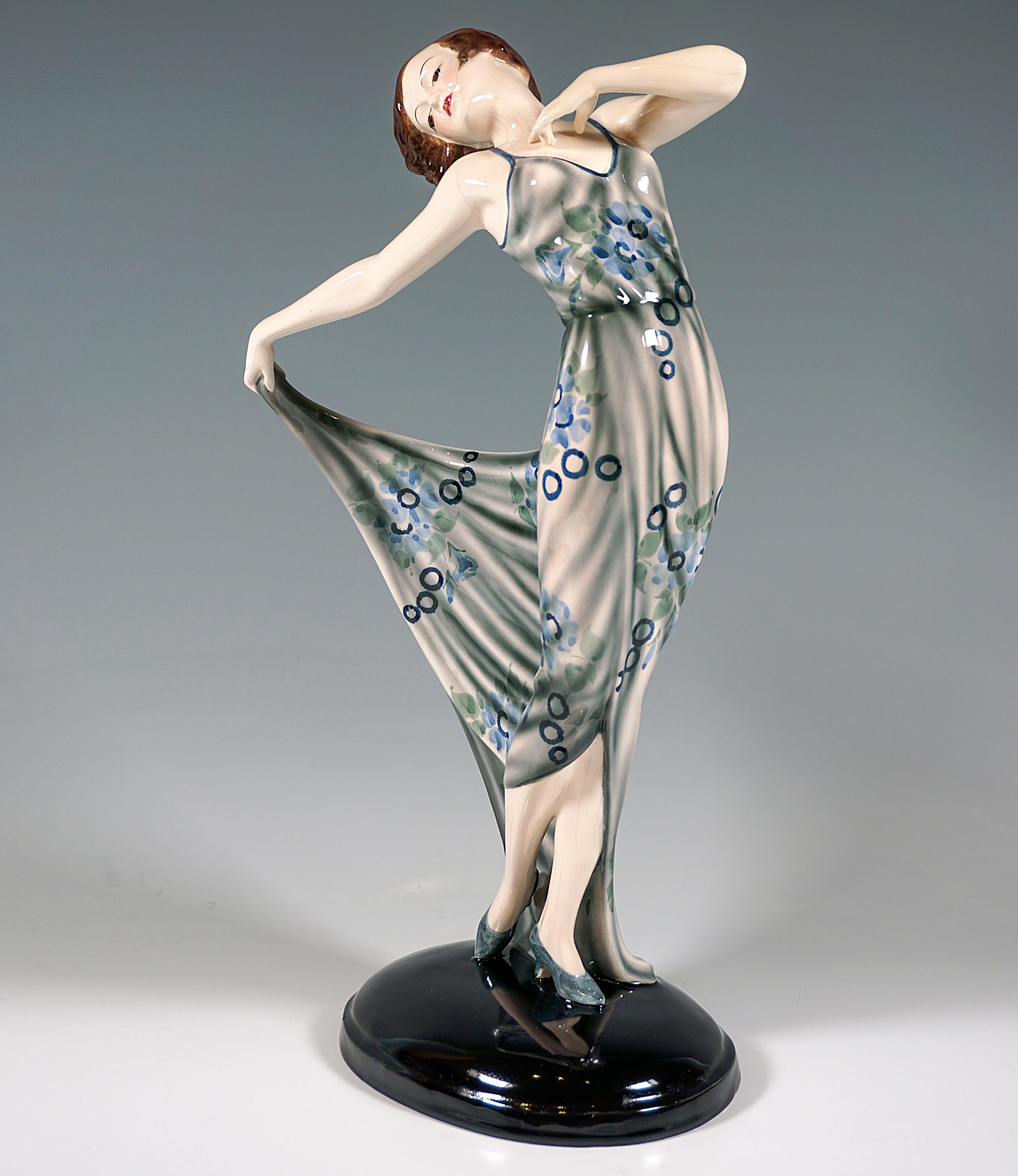 Elegant Goldscheider Art Déco art ceramic figure from the 1930s: 
Dancer with chin-length brunette hair in light gray-blue long dance dress with abstract floral decoration, posing with her upper body turned slightly to the side and leaning