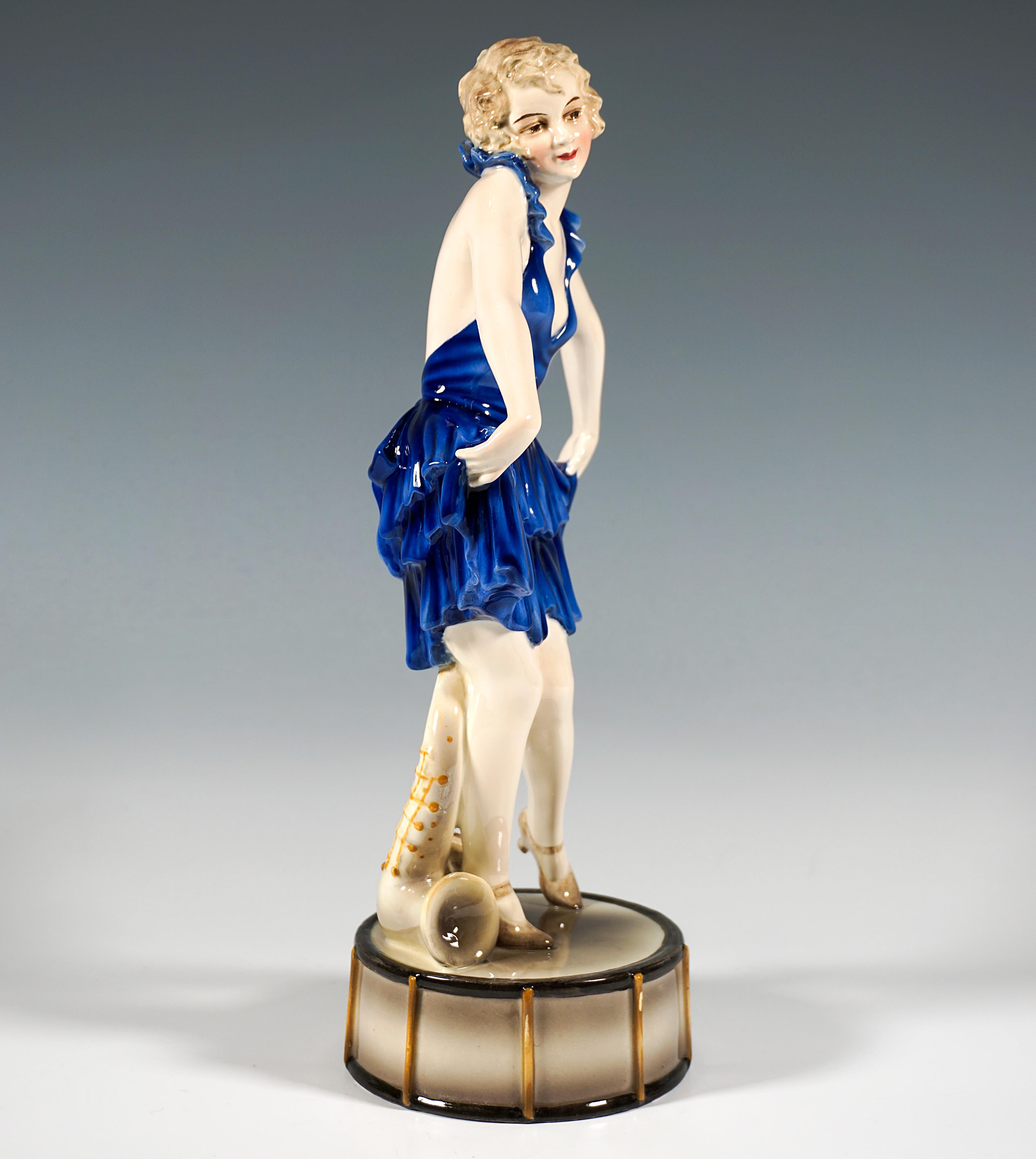 Rare Goldscheider Art Deco ceramic figure of the 1920's:
Depiction of a young vaudeville dancer posing in a short, low-cut, backless, blue dress with ruffled flounces and a bow, holding up the hem of her skirt on both sides and curtsying.
The young