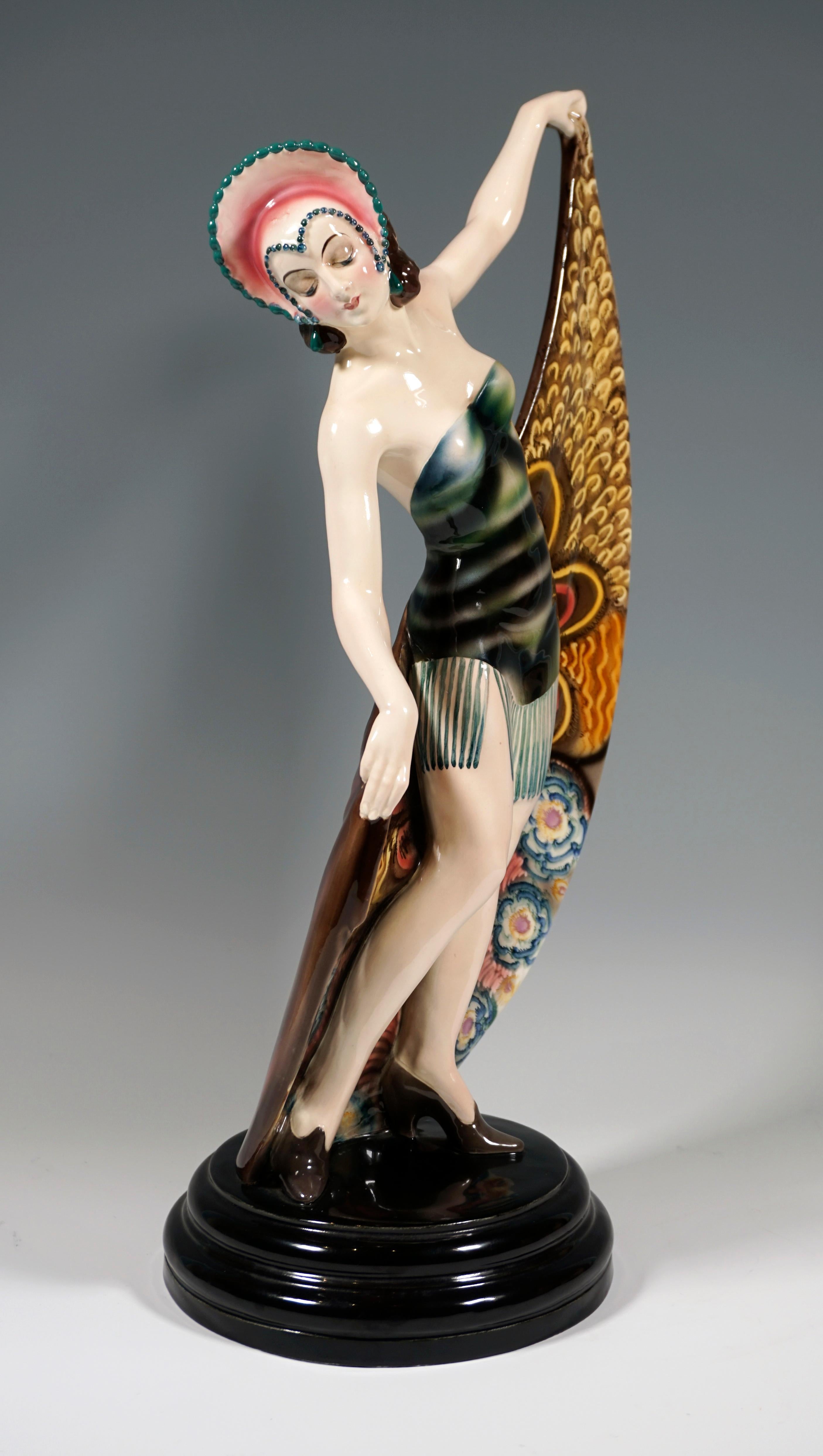 Seltene Goldscheider Art Deco Keramikfigur aus den 1920er Jahren: 
Darstellung einer Tänzerin in Pose. Sie trägt einen Kopfschmuck, der vorne spitz zuläuft und ihr Gesicht umrahmt, und ein kurzes, trägerloses Kleid mit langen Fransen. Mit geneigtem