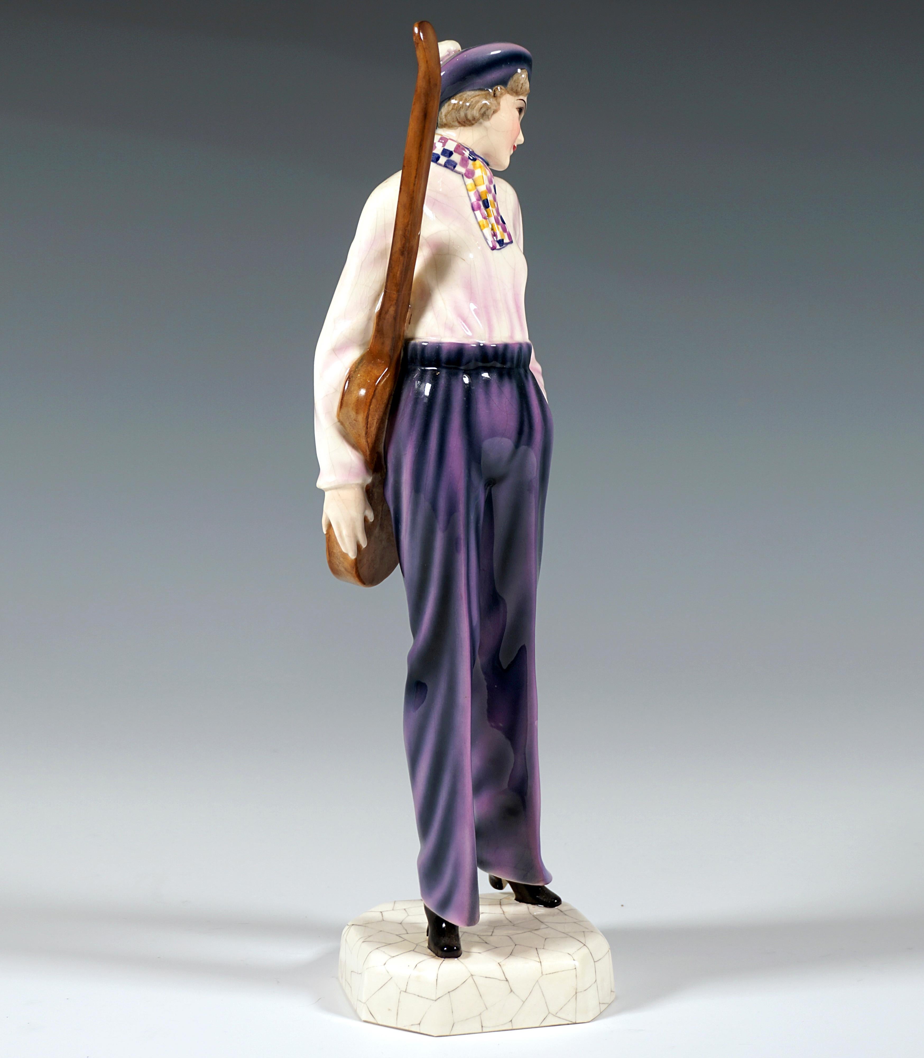 Very rare art ceramic figurine from the early 1930s:
Standing young lady with a pullman cap and bob hairstyle, head turned to the left, in a long-sleeved shirt with wide sleeves and long, straight trousers with creases, checkered scarf, a guitar