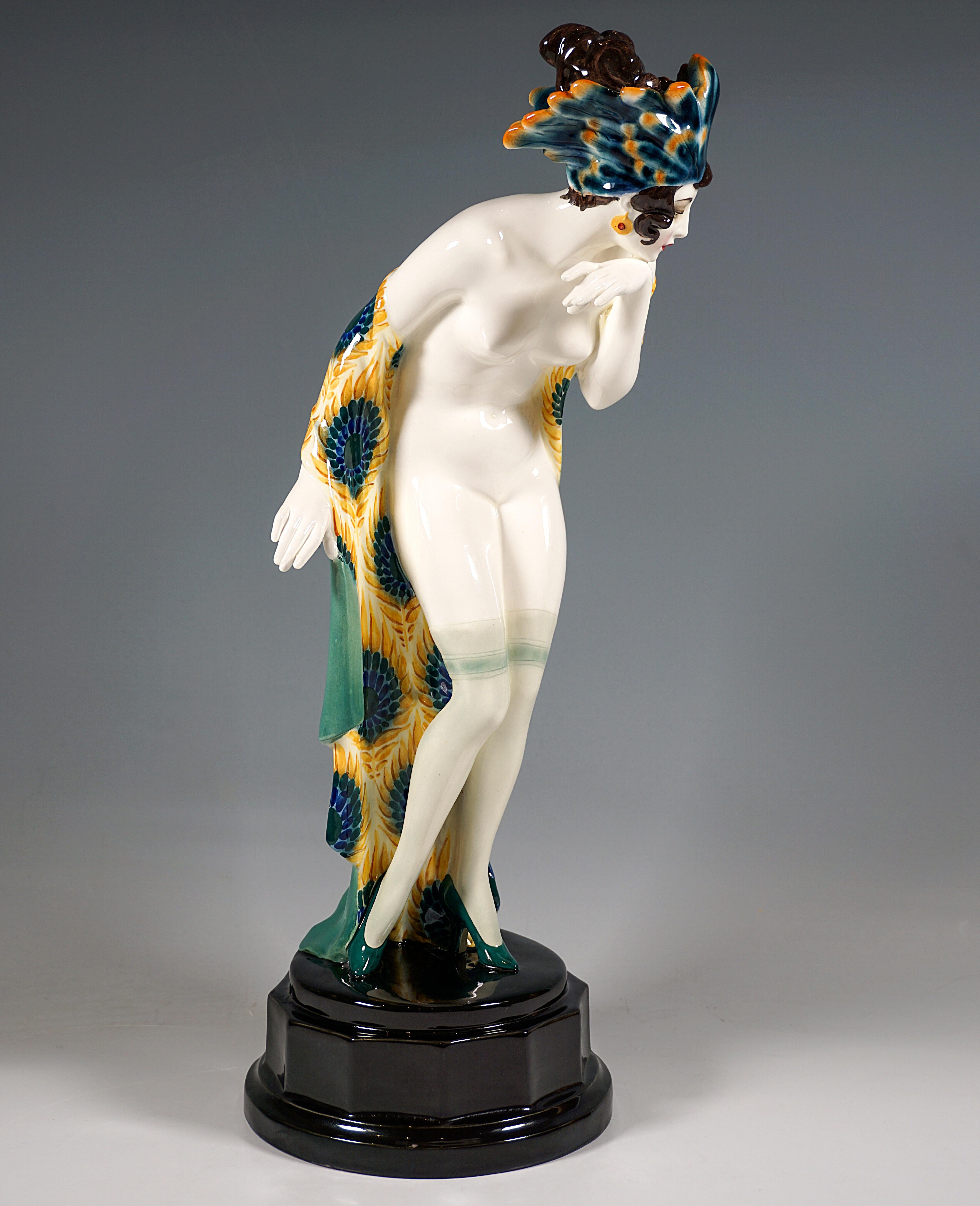 Impressive Goldscheider Vienna Ceramic Figurine of the 1920s:
The young lady with artfully pinned hair wears only transparent stockings and high heels, as well as a headdress densely decorated with shaded turquoise-yellow feathers, a green-turquoise