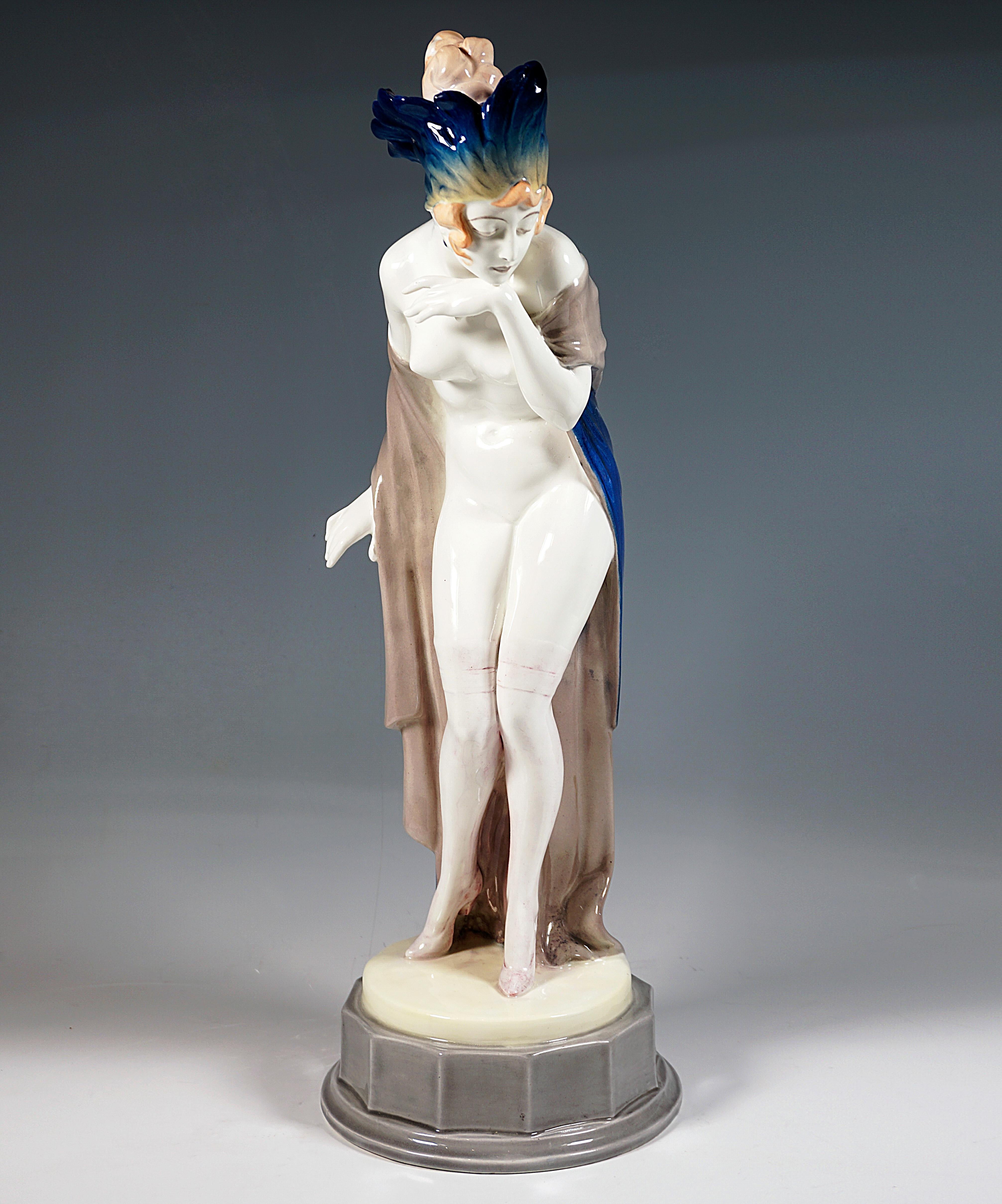 Beeindruckende Goldscheider Wiener Keramikfigur aus den 1920er Jahren:
Die junge Dame mit kunstvoll hochgestecktem Haar trägt nur durchsichtige Strümpfe und hohe Absätze sowie einen dicht mit blau-gelb schattierten Federn geschmückten Kopfschmuck,